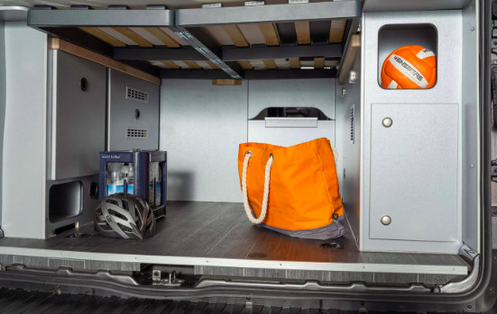 Ample RV rental storage: a camper van's organized rear space holding water bottles, a helmet, and a ball under the bed.. Weinsberg Caratour Ford 550 MQ 2024