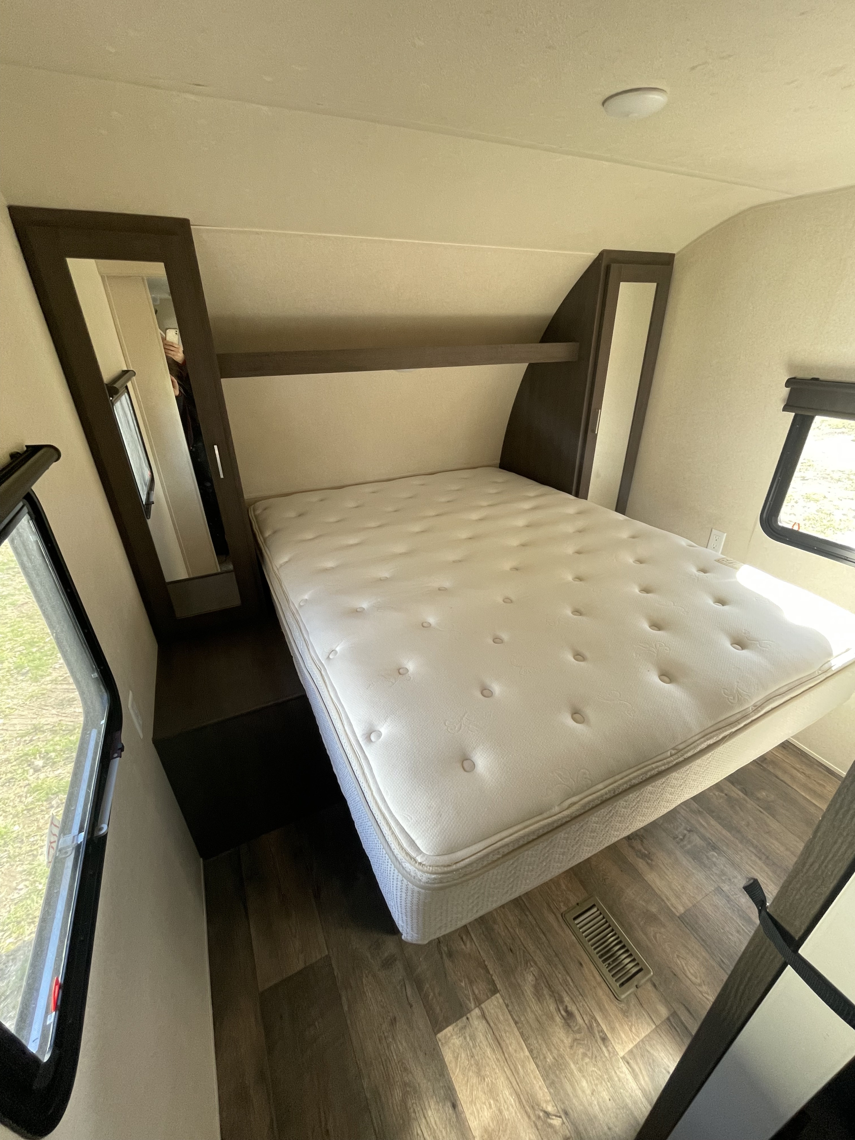 A well-appointed RV rental bedroom, with a queen-size bed, mirrored wardrobe, overhead shelf, and side windows.. Forest River Salem 2018