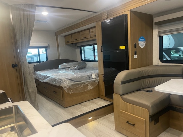 Spacious RV rental interior featuring a cozy bedroom, full kitchen, dining area, and refrigerator for comfortable travel.. Coachmen LEPRECHAUN 230FS 2025