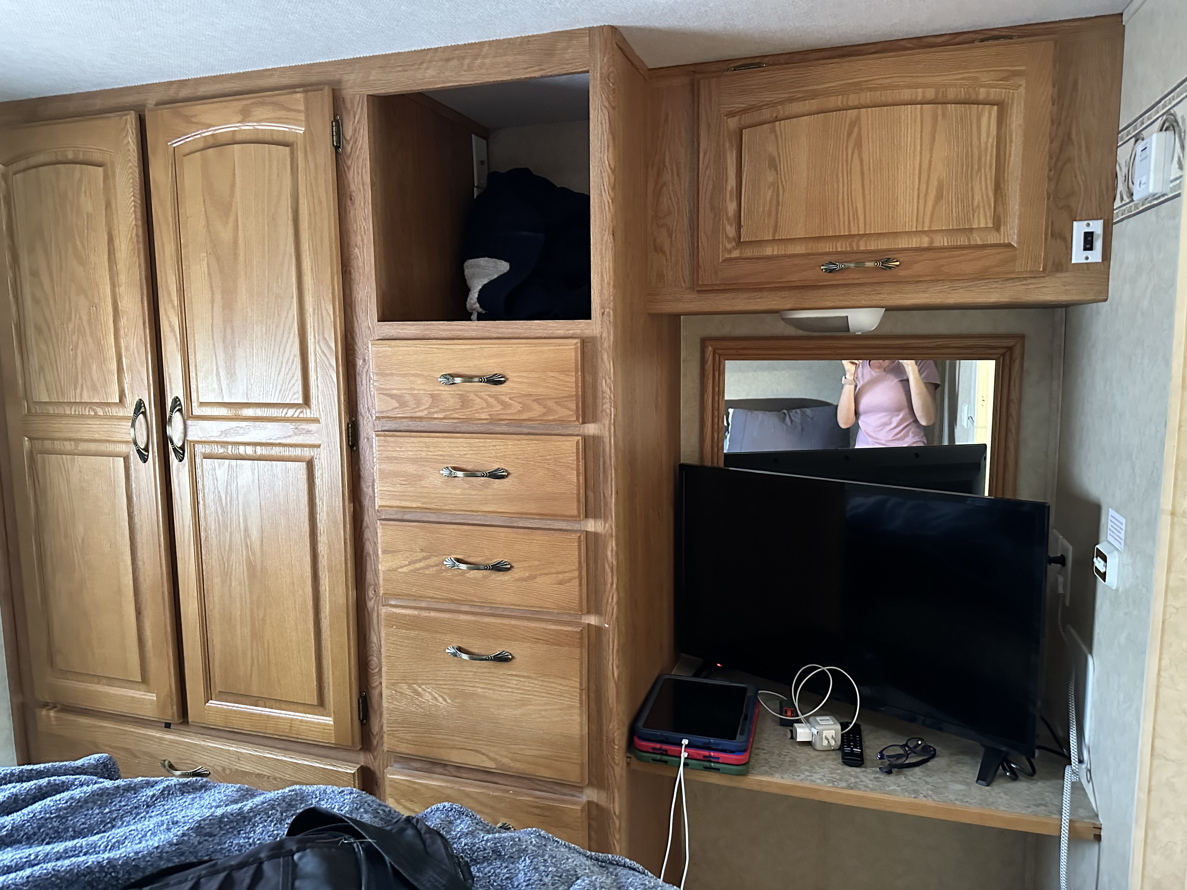 RV rental: Functional RV bedroom with ample wooden storage, TV, and charging area for devices.. Jayco Greyhawk 2006