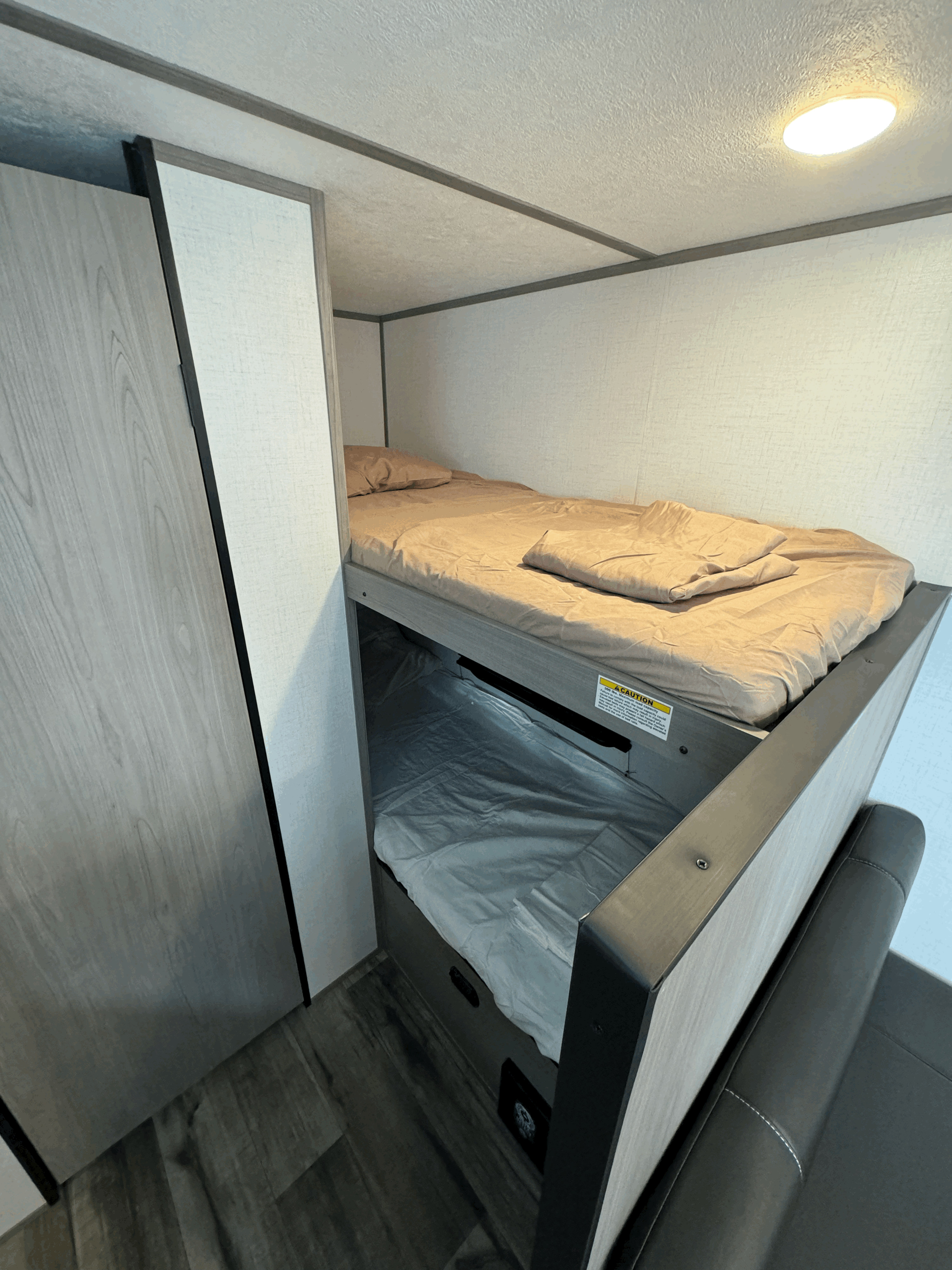 RV rental: Compact sleeping area with upper and lower bunk beds, a wardrobe, and overhead light in the interior.. dutchmen coleman 17B 2024