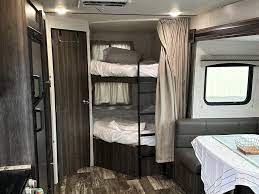 RV rental interior: bunk beds visible left of center, with a dinette and window on the right. Modern, cozy camper setup.. Starflyer Starcraft 2020