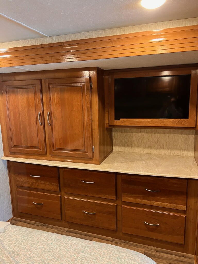 RV rental: warm wood cabinets, numerous drawers, & built-in TV in a compact, organized interior bedroom space.. Forest River Mirada 2019