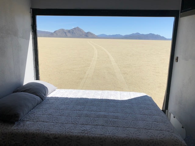 Stunning RV rental view from bed: tire tracks on the vast desert floor leading to distant mountains under a blue sky.. Northwood Mfg Desert Fox 2003