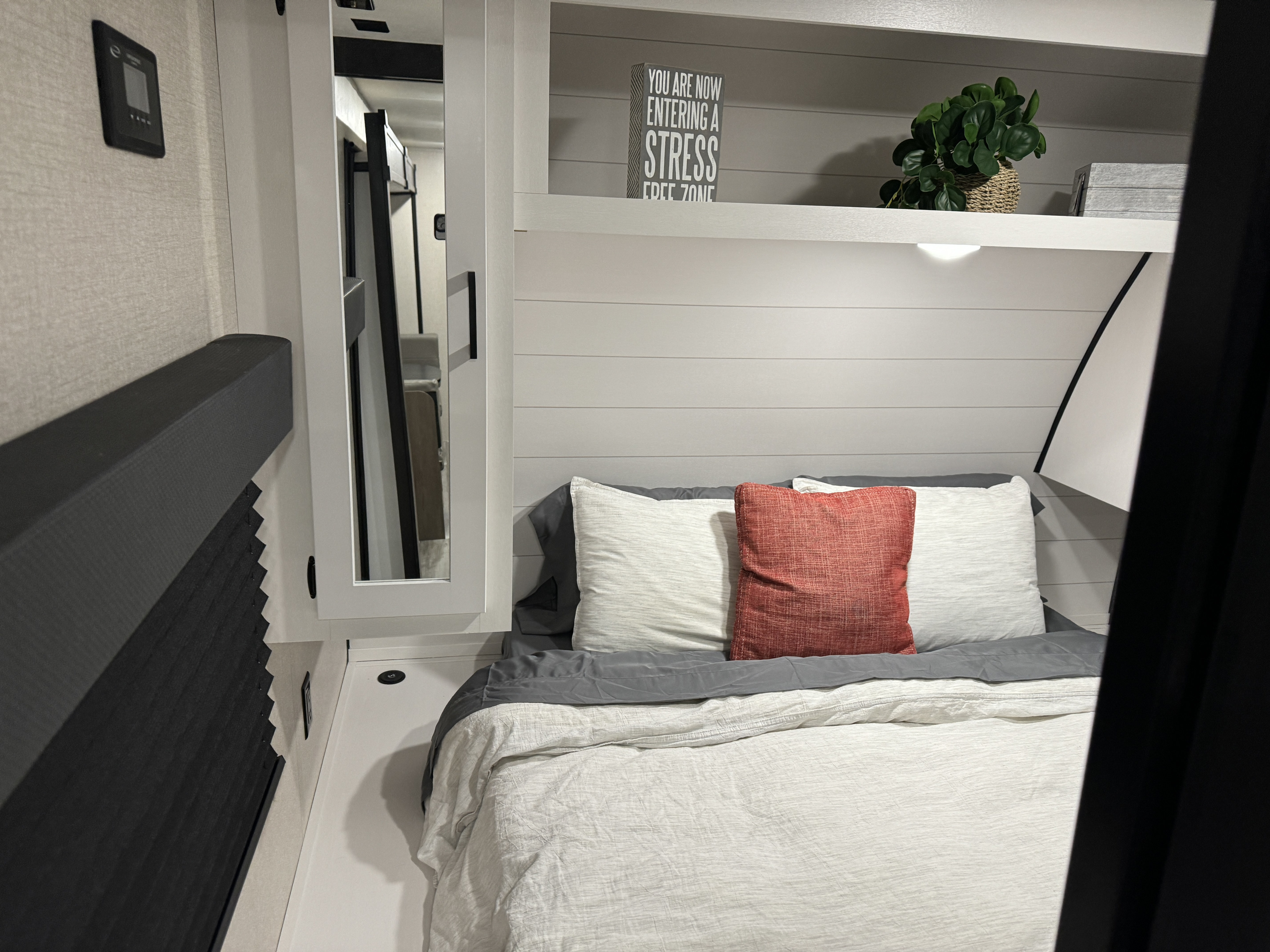 View inside a modern RV rental bedroom with a cozy bed, shiplap wall, and decor for a stress-free zone.. Starcraft 26BHS 2024