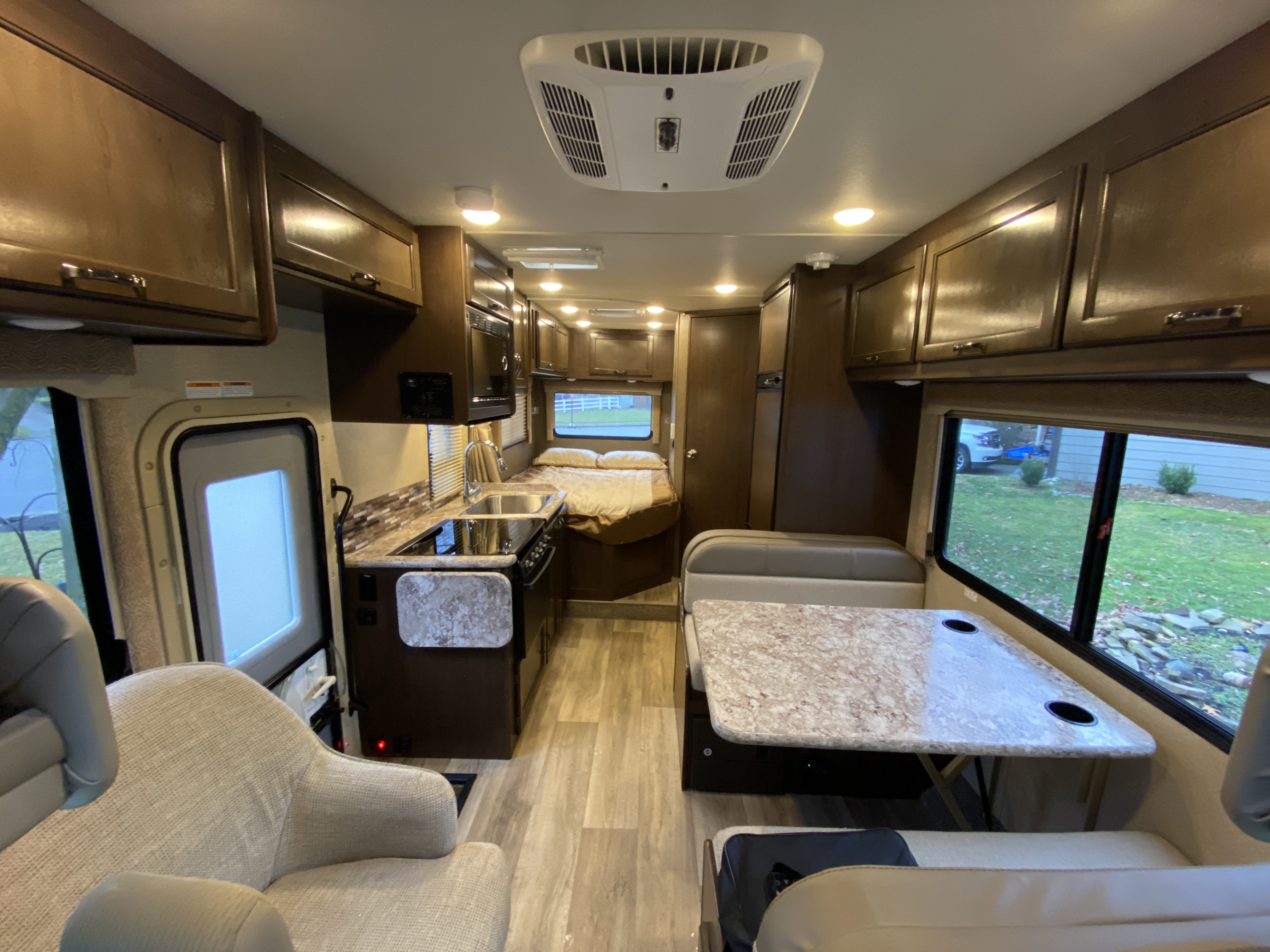 Inside a modern rv rental: full kitchen, dining area, rear bed, and comfy seating. Bright interior for your adventures.. Thor Freedom Elite 2018