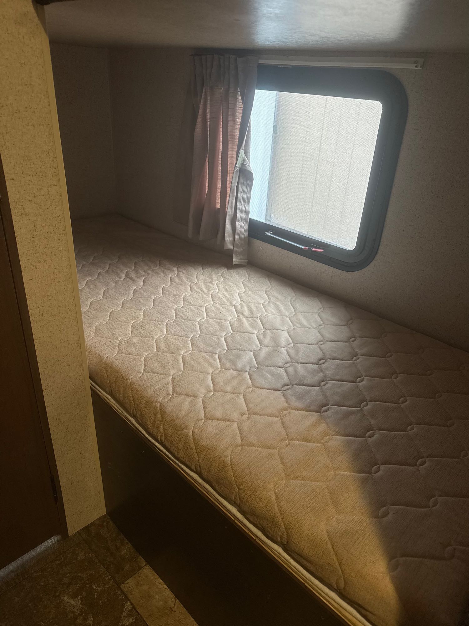 An RV rental features a comfortable single bunk bed with a window and curtains, a compact sleeping area.. Jayco Jay Flight SLX 2015