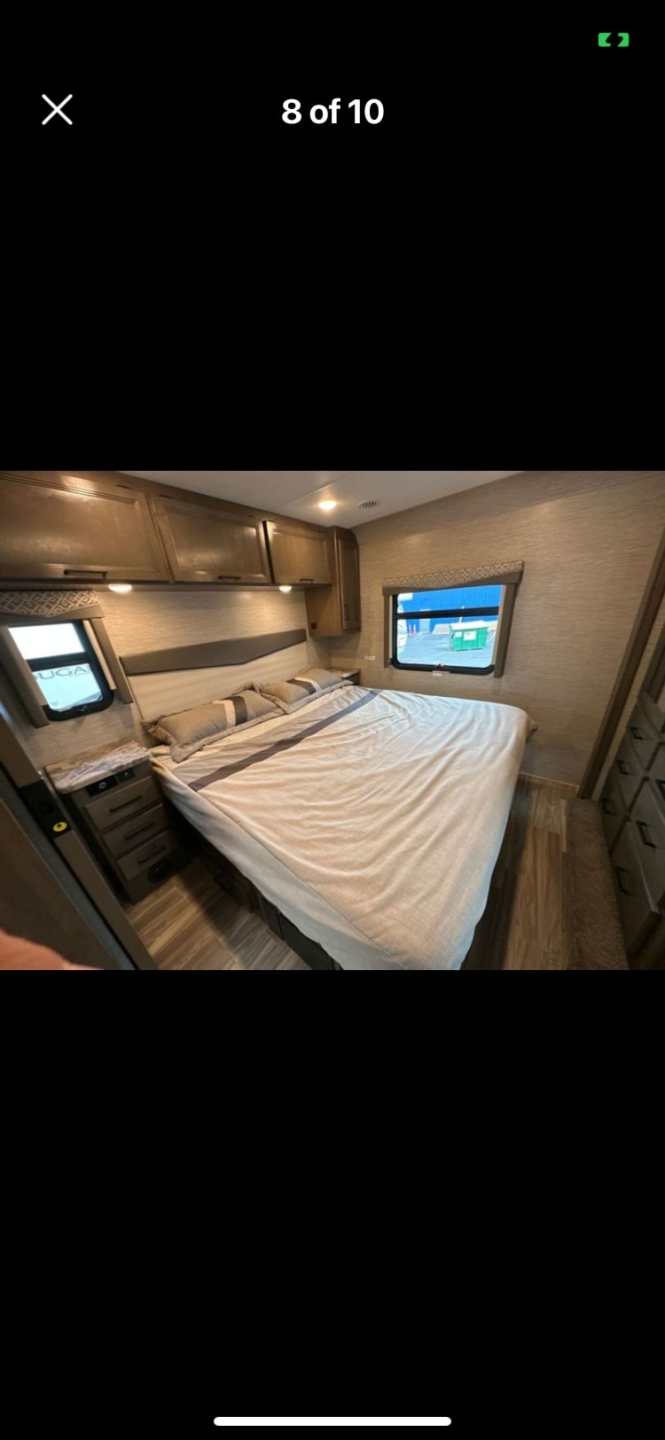 Cozy RV rental bedroom featuring modern wood cabinets, soft bedding, and window views for comfortable travel.. Thor A.C.E. 2022