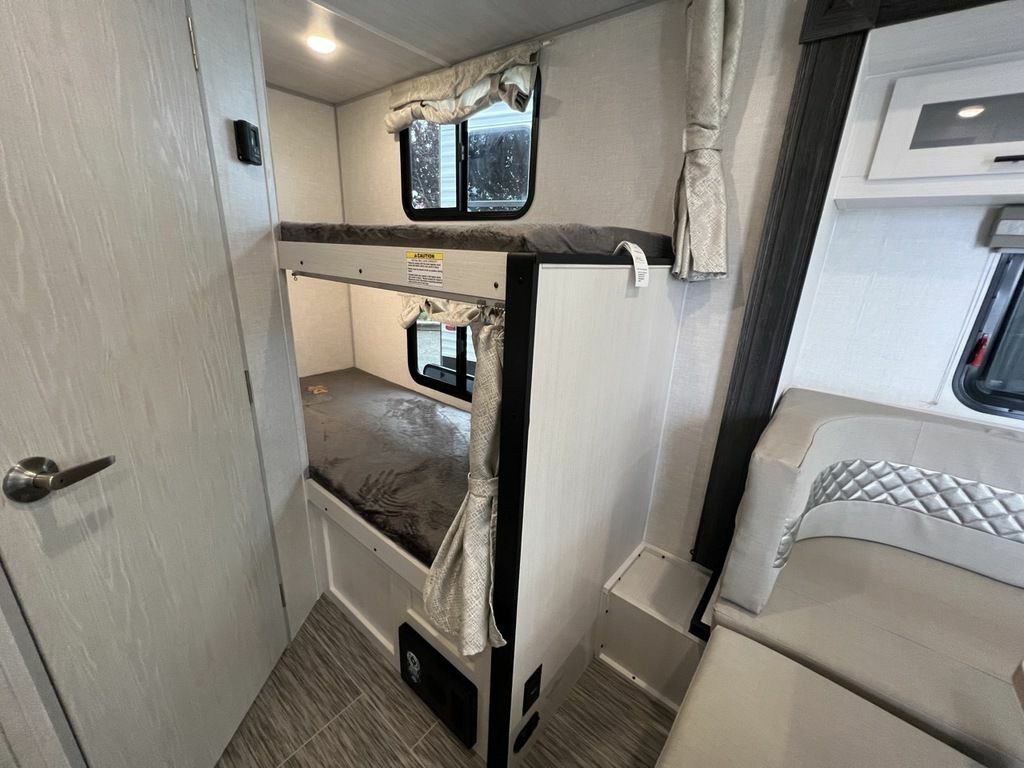 RV rental interior showcasing two bunk beds with windows and privacy curtains, next to a comfy dinette seating area.. Forest River NoBoundaries (NOBO) 2023