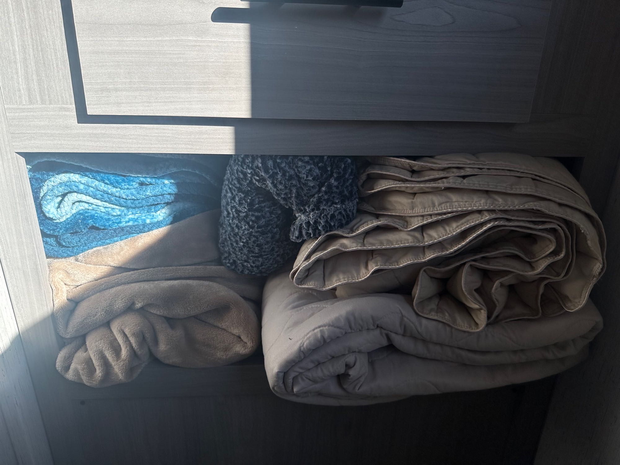 Cozy blankets and quilts neatly stored in an RV rental cabinet. Essential linens for comfortable travel.. Dutchman Coleman Lantern 2022