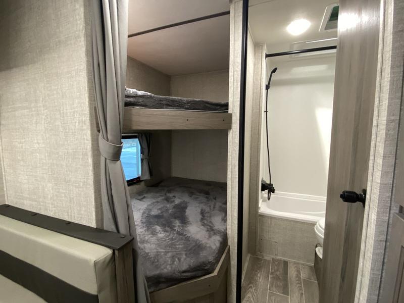 RV rental interior features bunk beds with privacy curtain and a compact bathroom with shower and toilet.. Grand River 25BH 2024