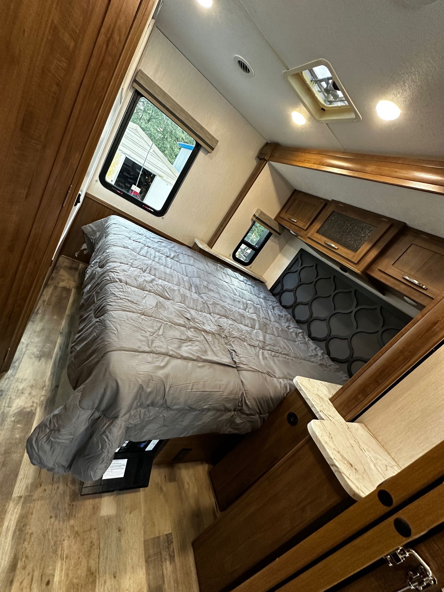 Spacious RV rental bedroom with a comfy bed, wood cabinets, and large windows. Ready for your adventure!. Forest River Coachmen Pursuit 2020