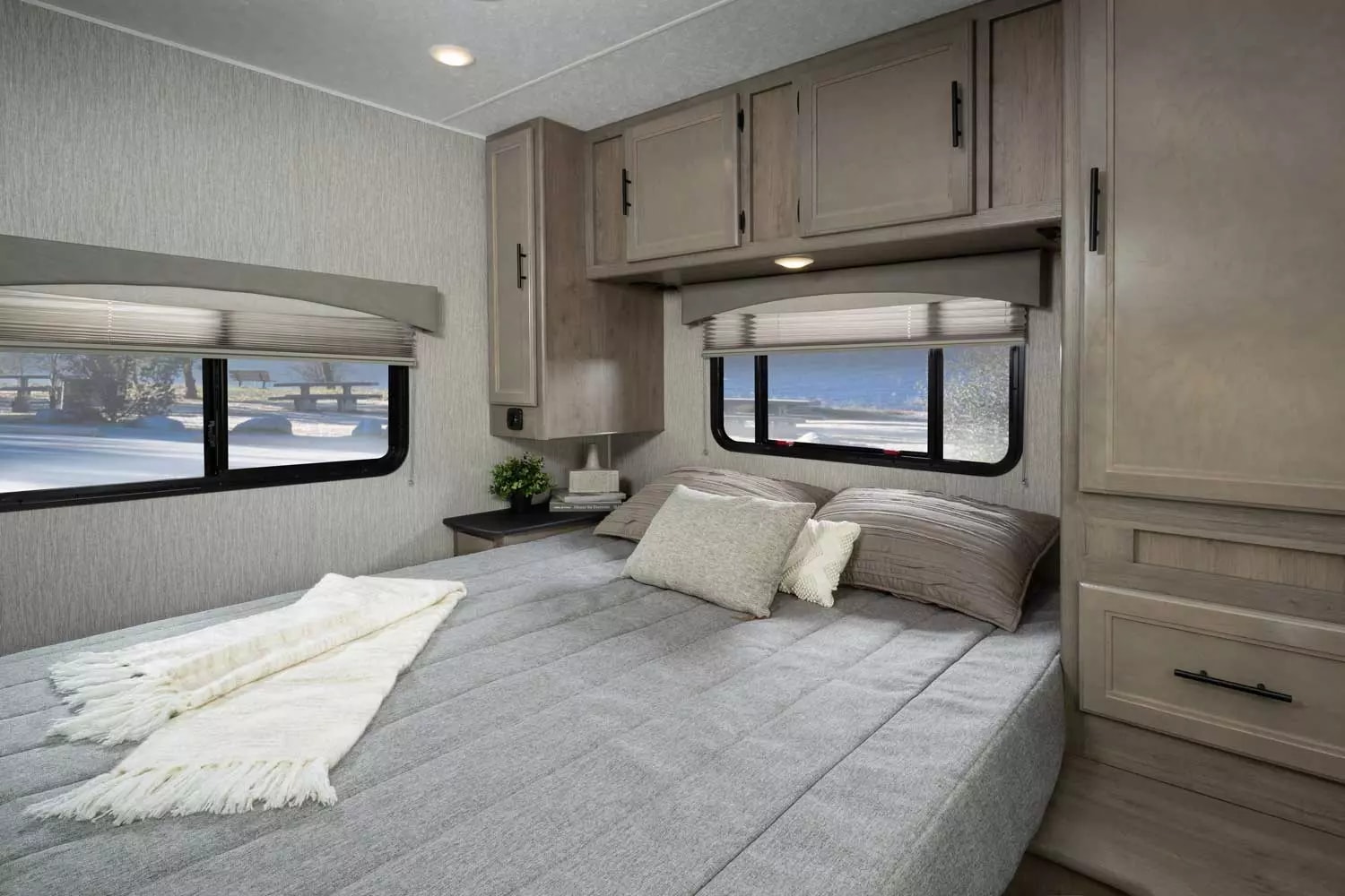 Cozy RV rental bedroom offers comfort with a large bed, ample storage, and scenic winter window views.. Freelander Coachman 2023