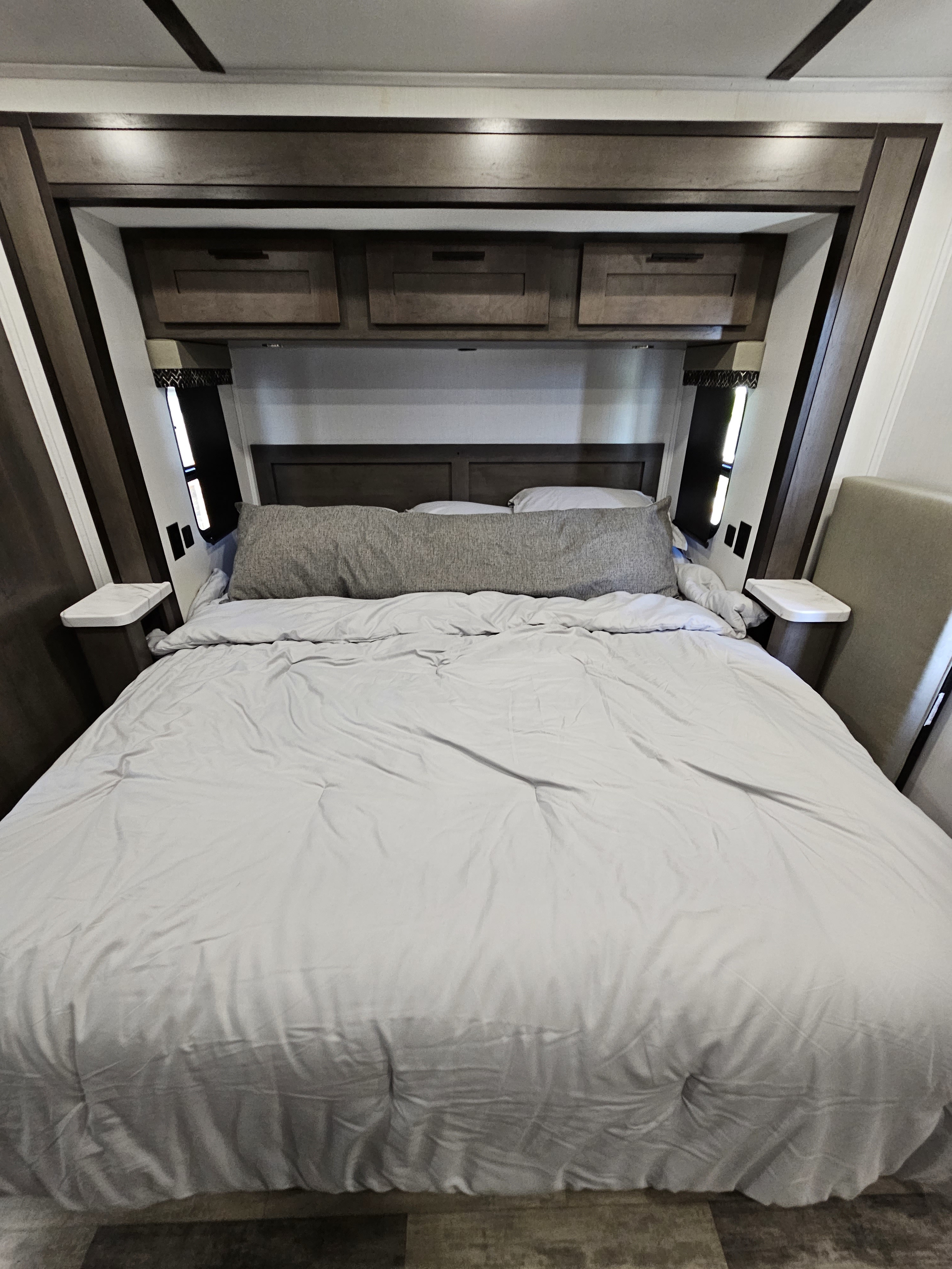 Spacious, modern RV rental bedroom with comfortable bed, overhead storage, and built-in features for a cozy trip.. FR3 FR3 Motorhome 2023