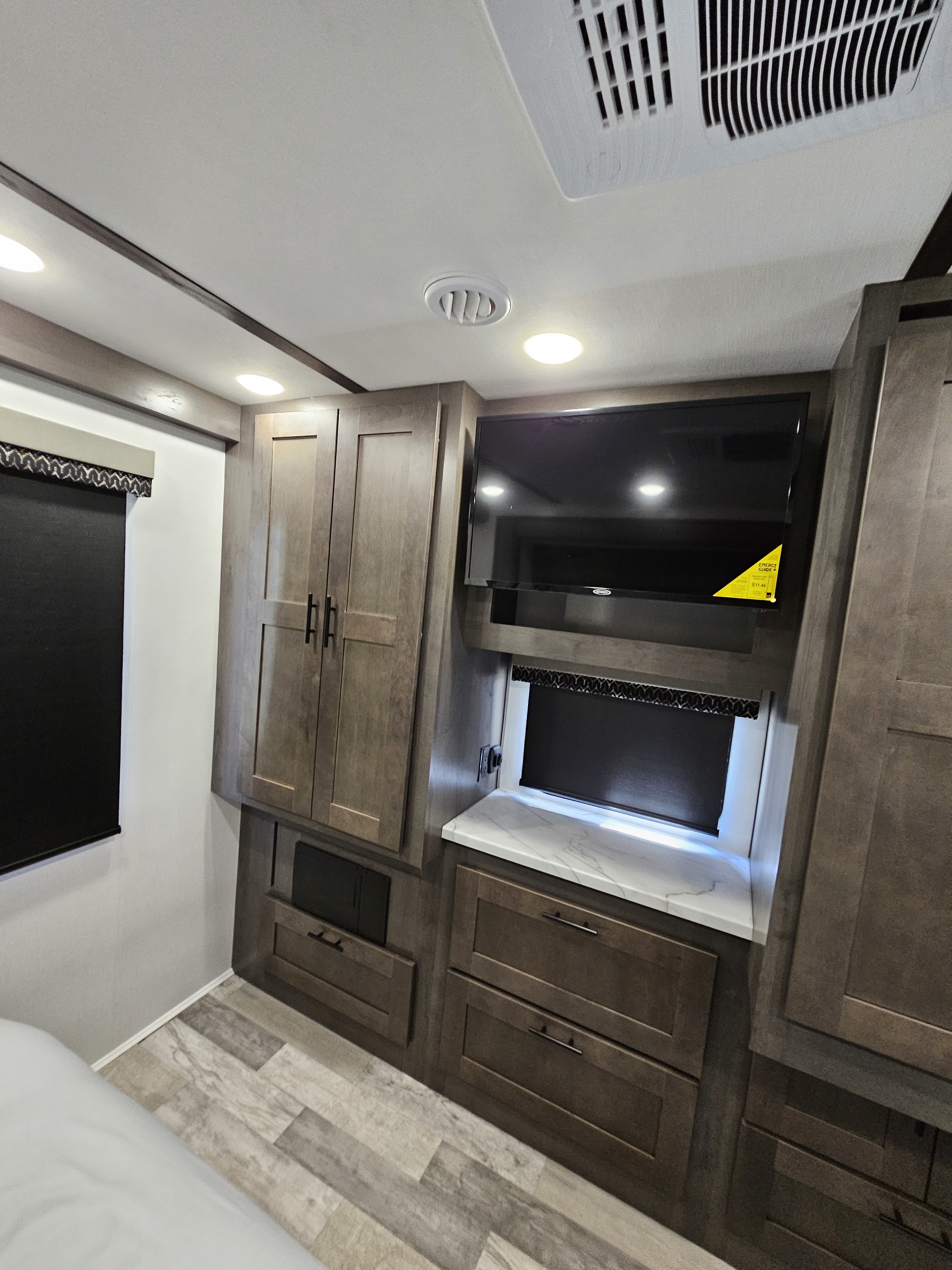 This RV rental bedroom features a wall-mounted TV, wood-toned cabinets, recessed lighting, and an AC unit for comfort.. FR3 FR3 Motorhome 2023