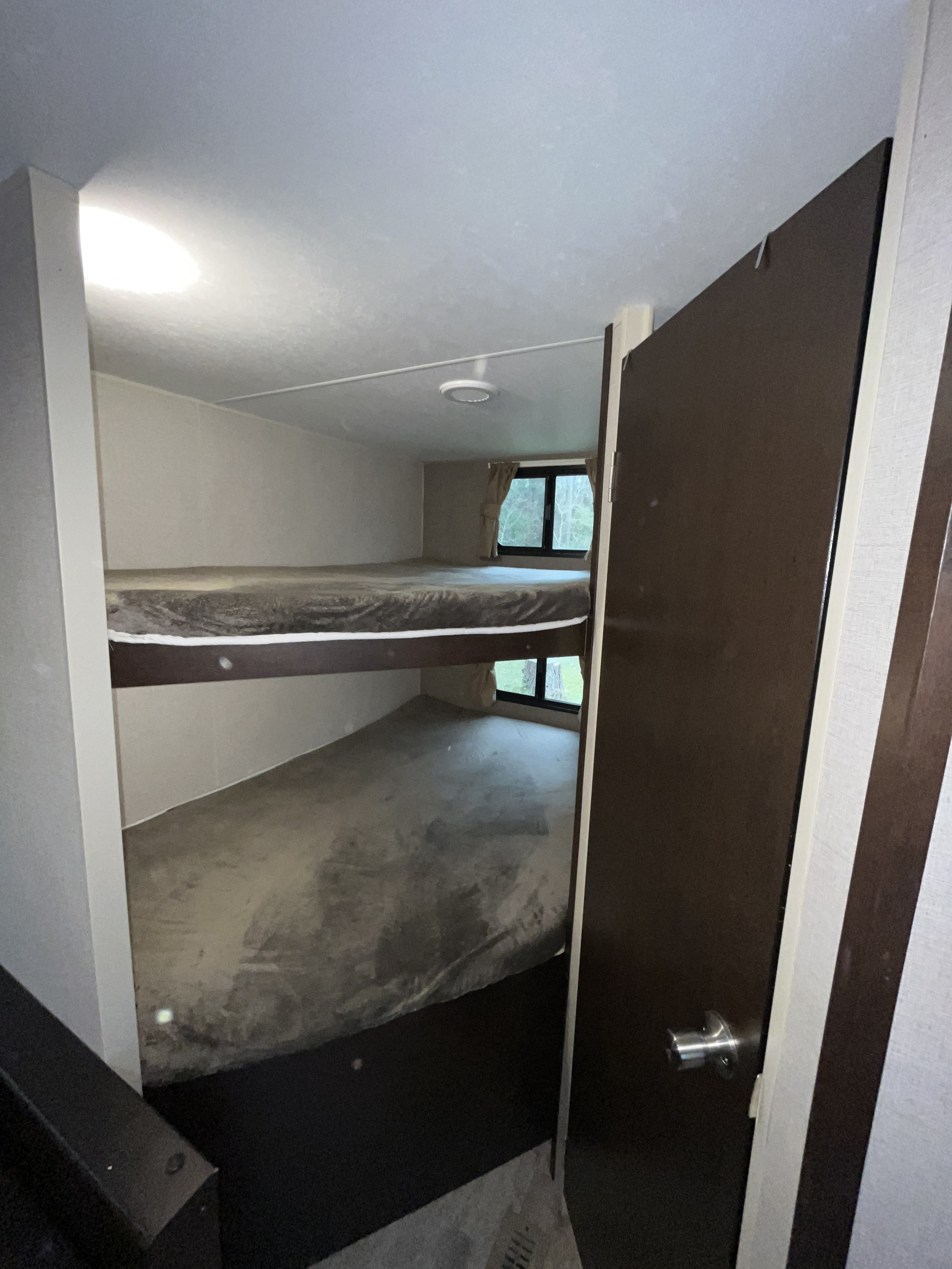 RV rental bunk beds: A view of the sleeping area inside an RV, showing two stacked beds with a window on the lower bunk.. Sportsmen LE 2019