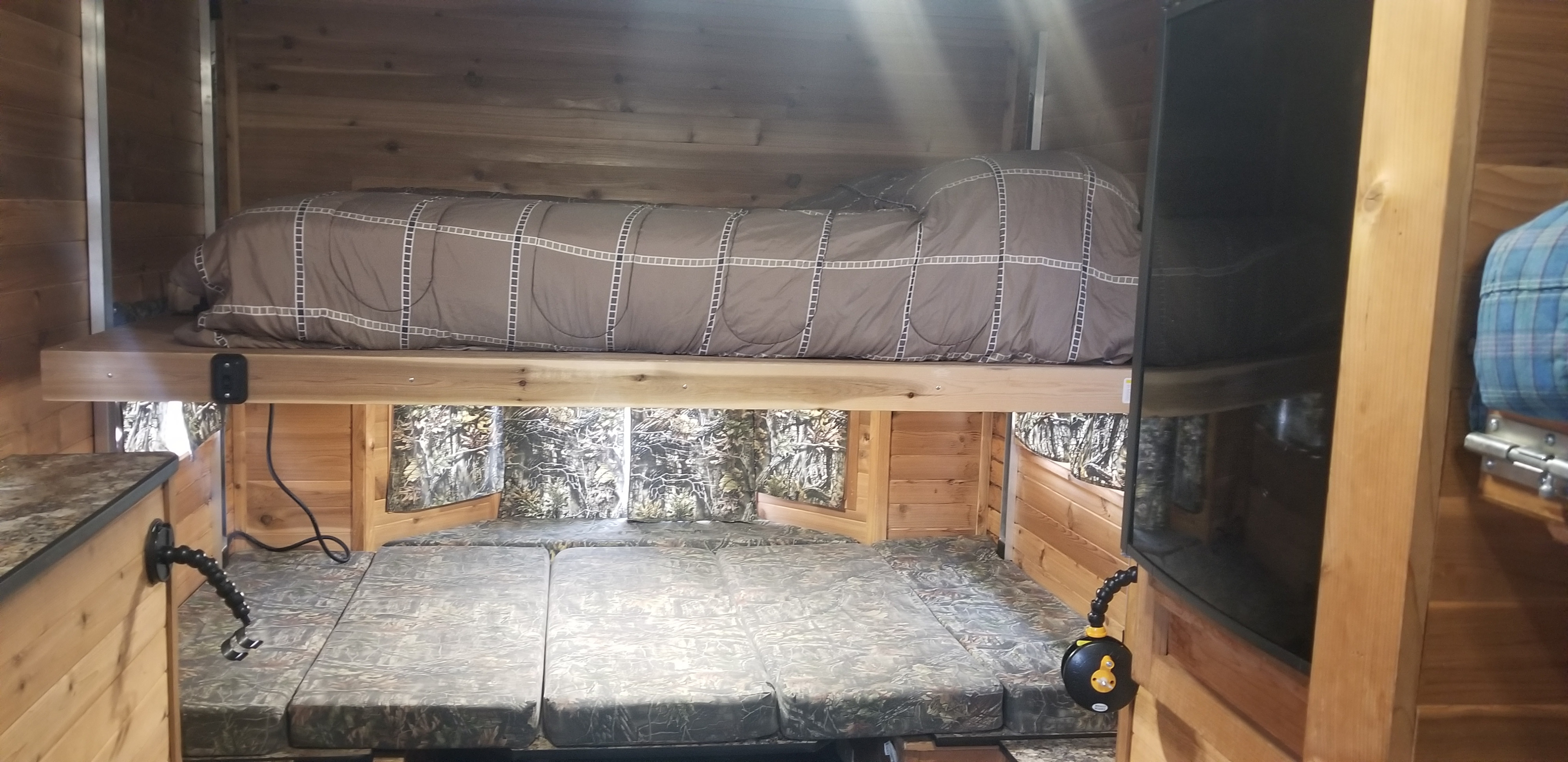 RV rental interior: A cozy sleeping space with a top bunk bed, patterned comforter, and a lower bed with camo cushions.. Ice Castle Fish Houses Ice Castle Fish Houses Trailer 2016