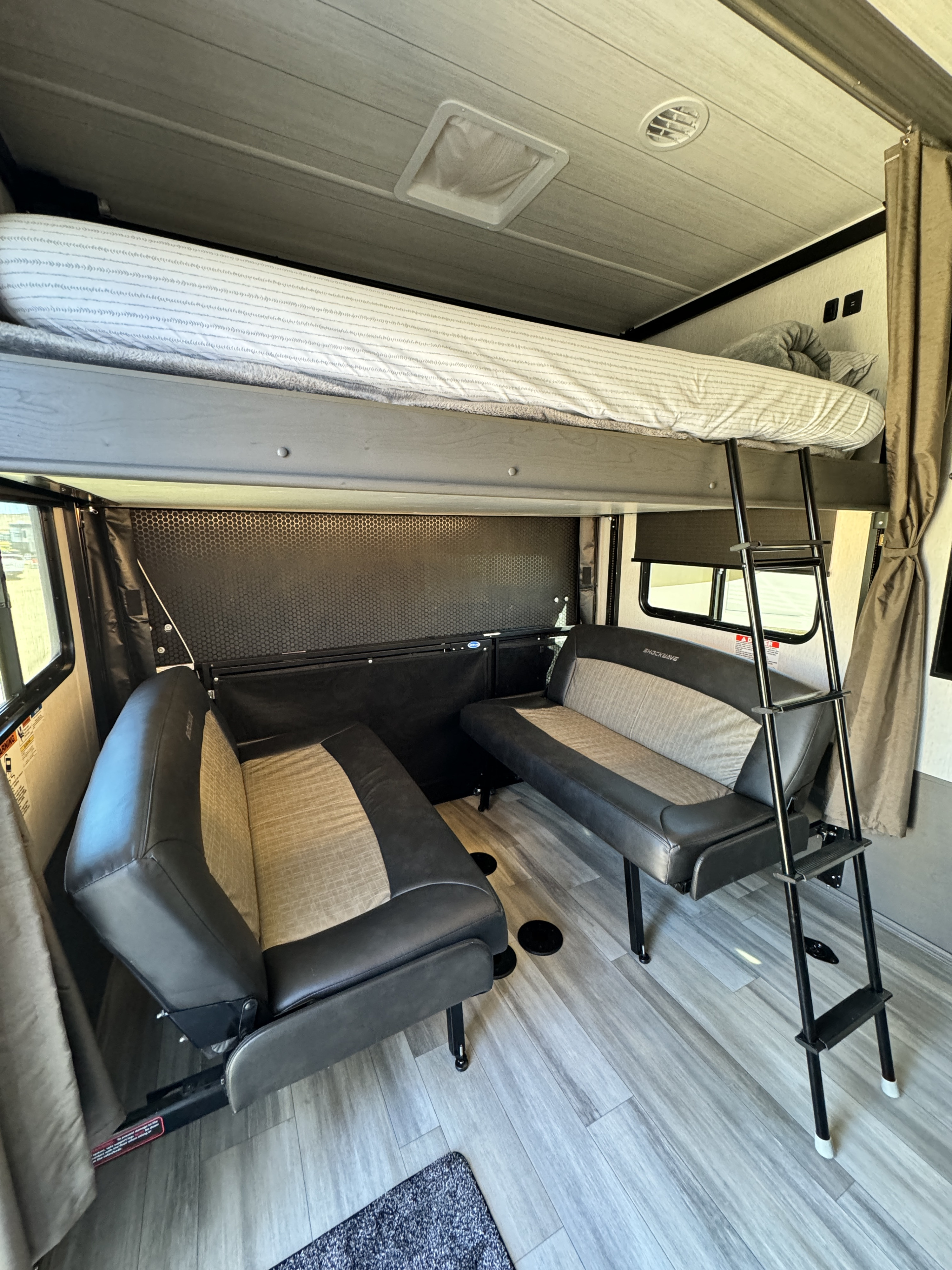 Interior of an **RV rental** showing a bunk bed, ladder, and two cushioned sofas for versatile seating.. Forest River Shockwave 2023