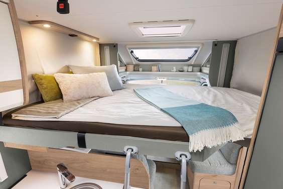 Comfortable RV rental: Spacious bed with skylight, pillows, and compact kitchen below for ideal trips.. Dethleffs Just T7052 DBM 2024