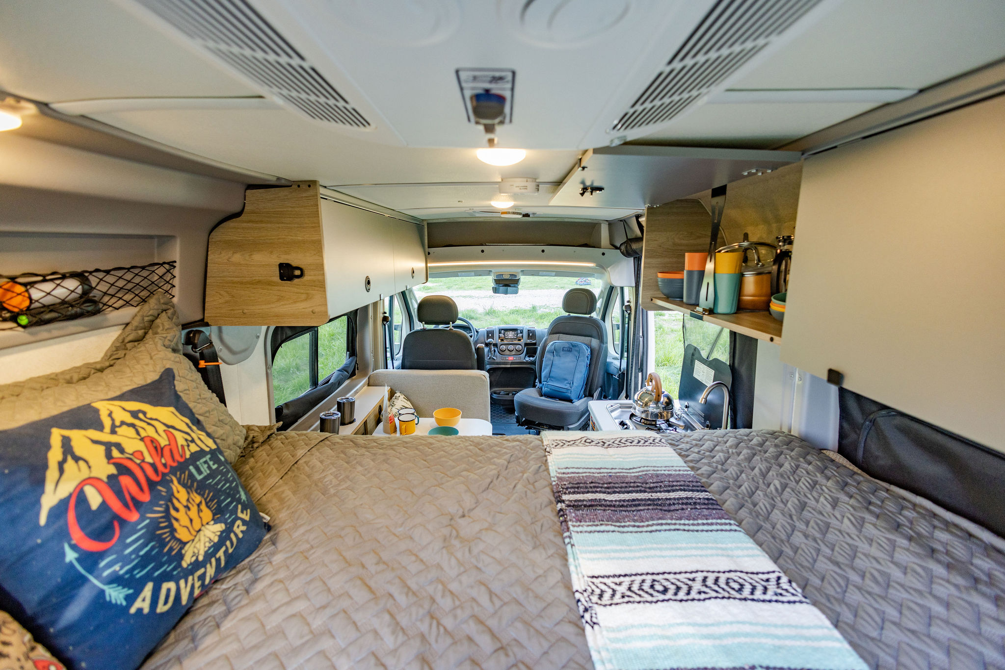 An RV rental's clever interior. From the comfy bed, see the compact kitchen, storage, and front cabin ready for travel.. Winnebago Solis Pocket 2022