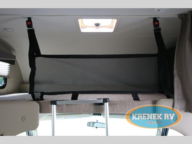 Inside an RV rental: An overhead bunk bed features a black safety net secured by straps, with a ladder for access. Ideal for kids.. Thor Chateau 2023