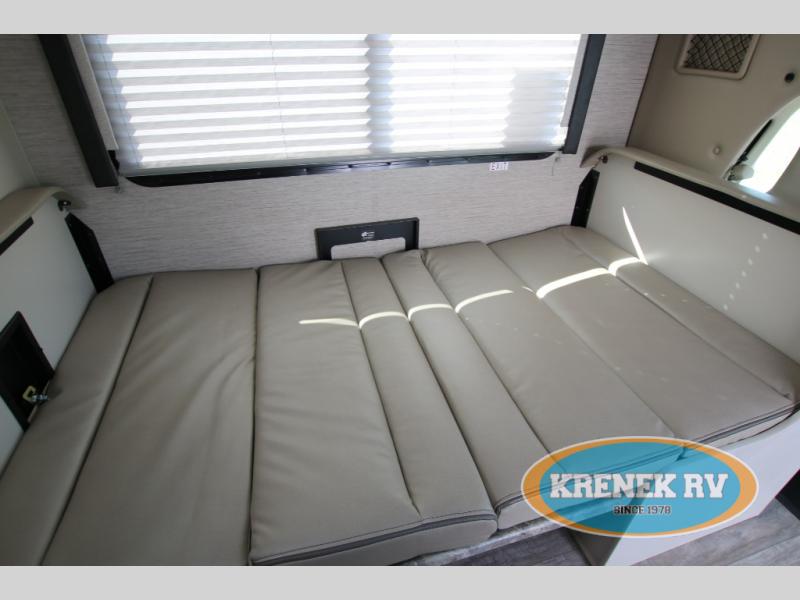 RV rental interior: A long, light-colored cushioned bed/seating area with window blinds above, perfect for a camper.. Thor Chateau 2023