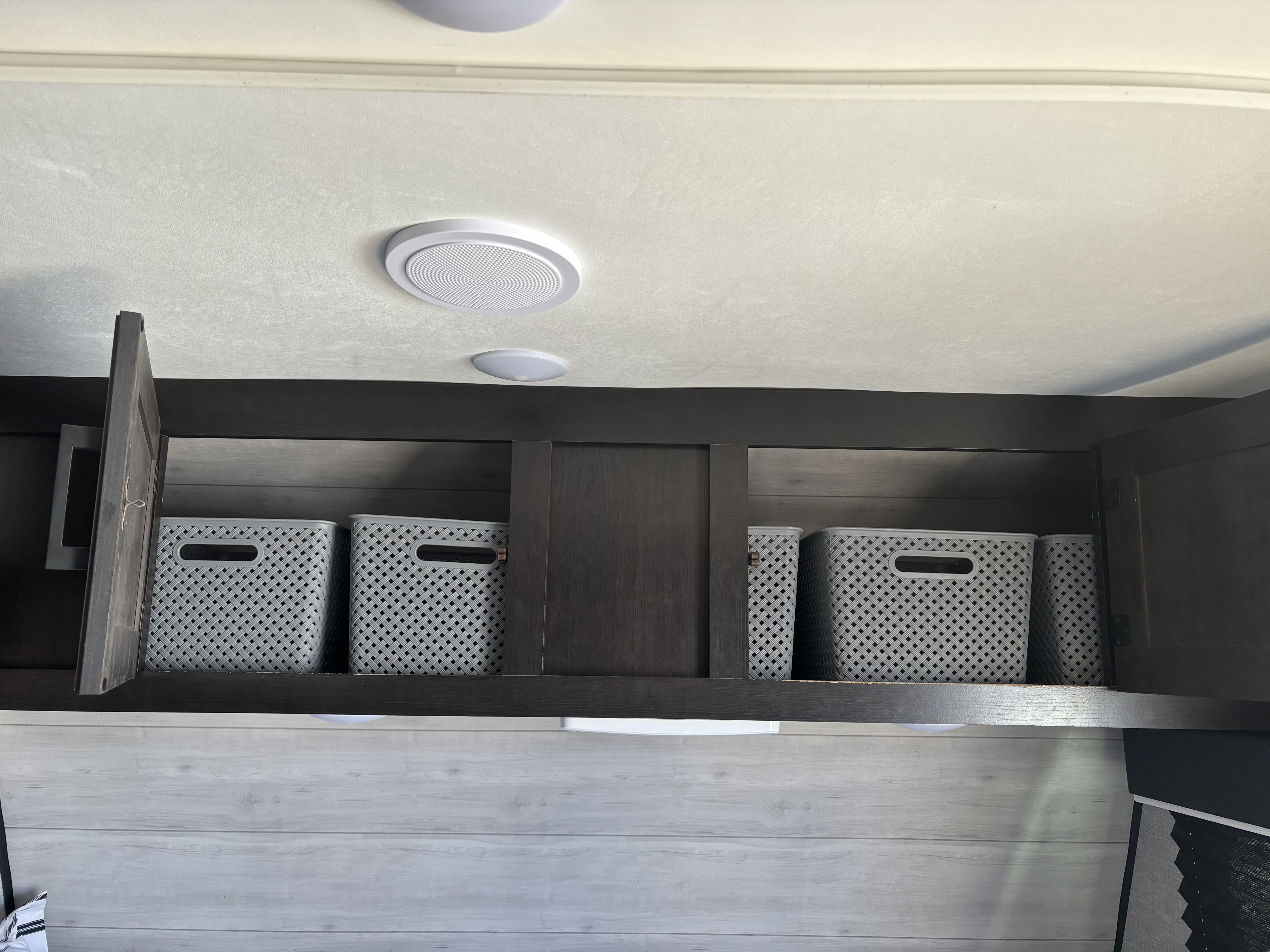 RV rental overhead storage: dark wood cabinets open to show gray patterned baskets, perfect for organizing travel essentials.. Jayco Jay Flight SLX Baja Edition 2022