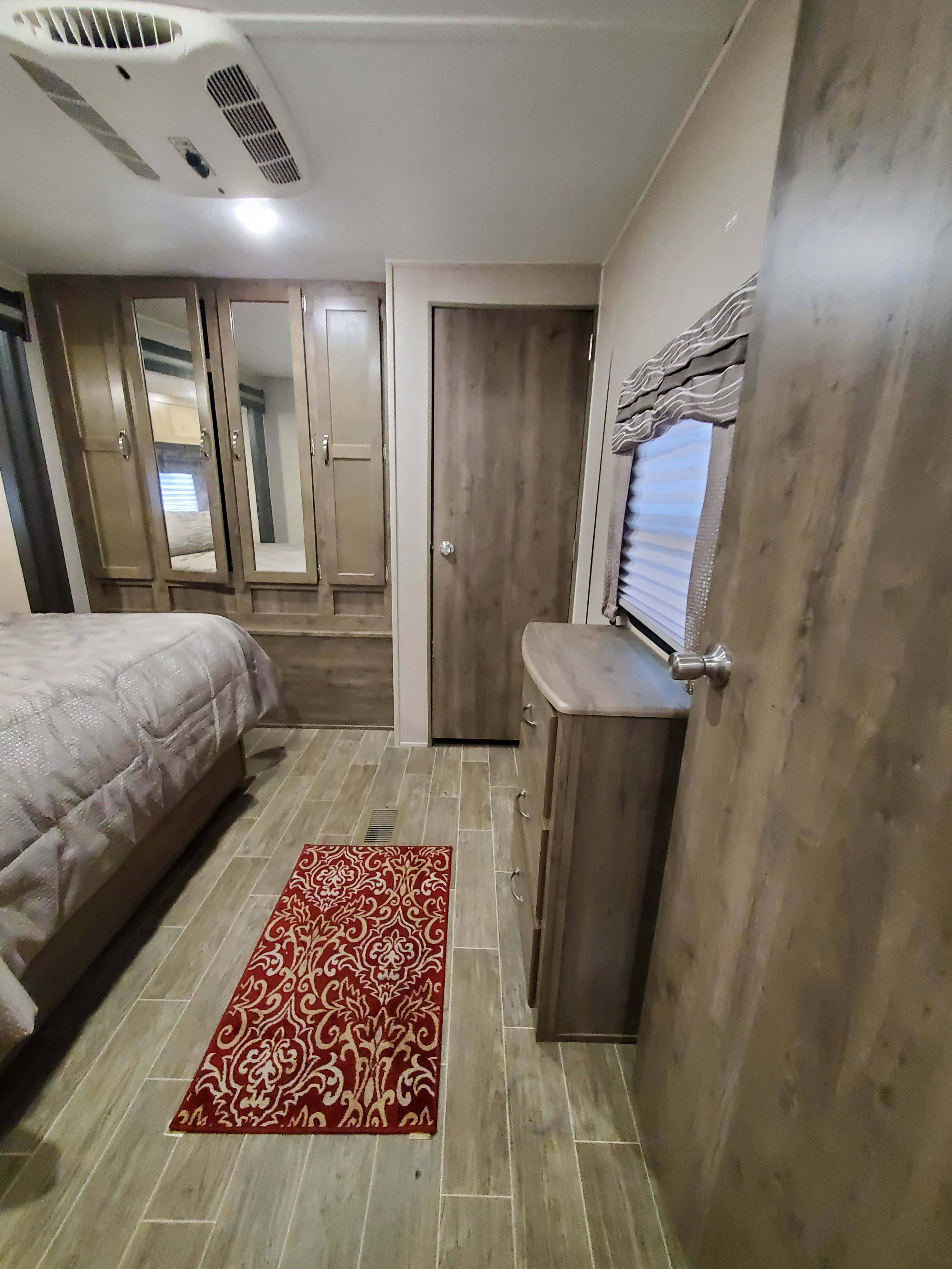 Cozy RV rental bedroom with mirrored wardrobe, comfortable bed, dresser, and ceiling AC unit.. Palomino Puma 2019