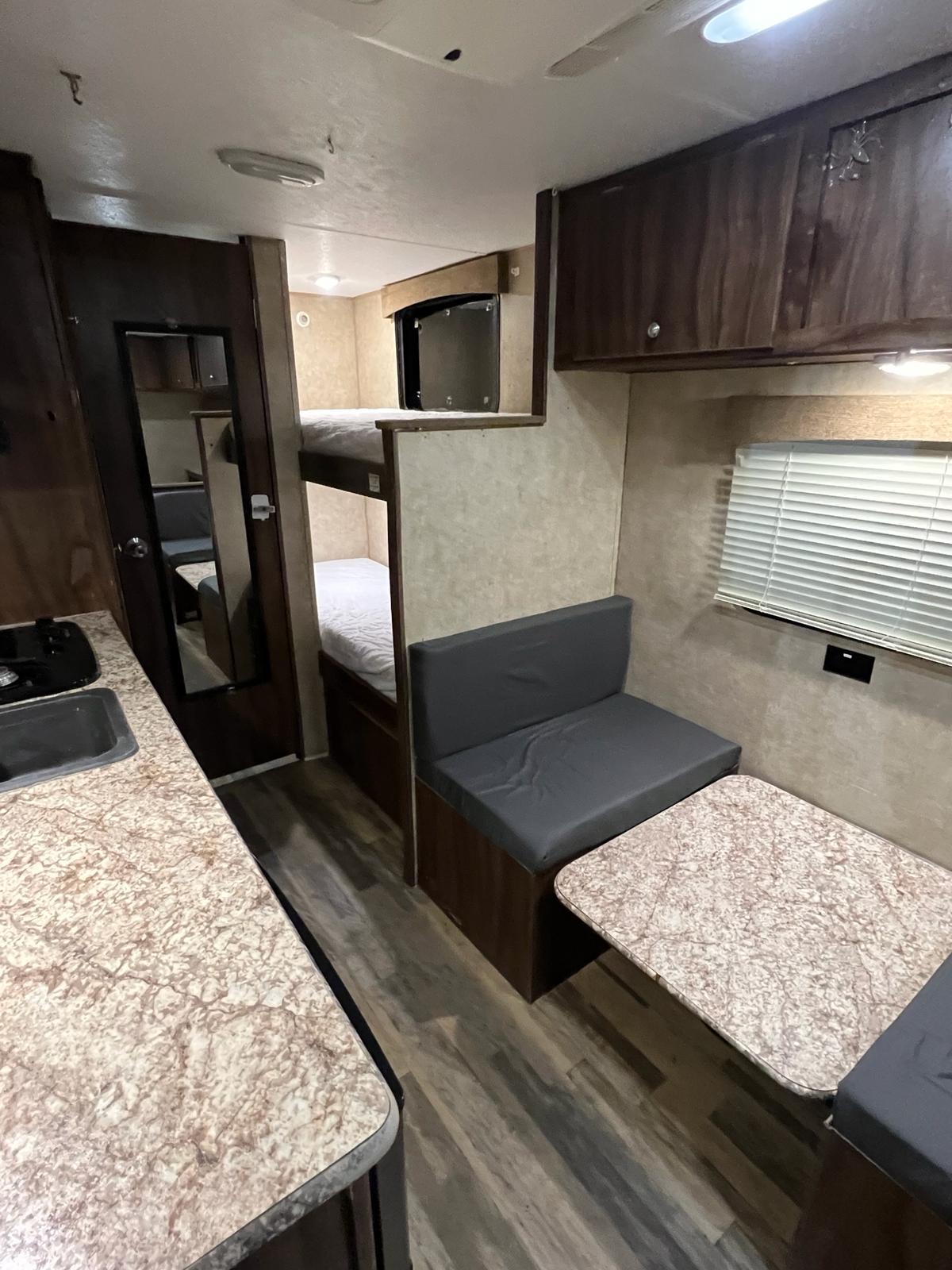 Cozy RV rental interior featuring a kitchen sink, bunk beds, and a dining area with seating.. Coachmen Viking 2018