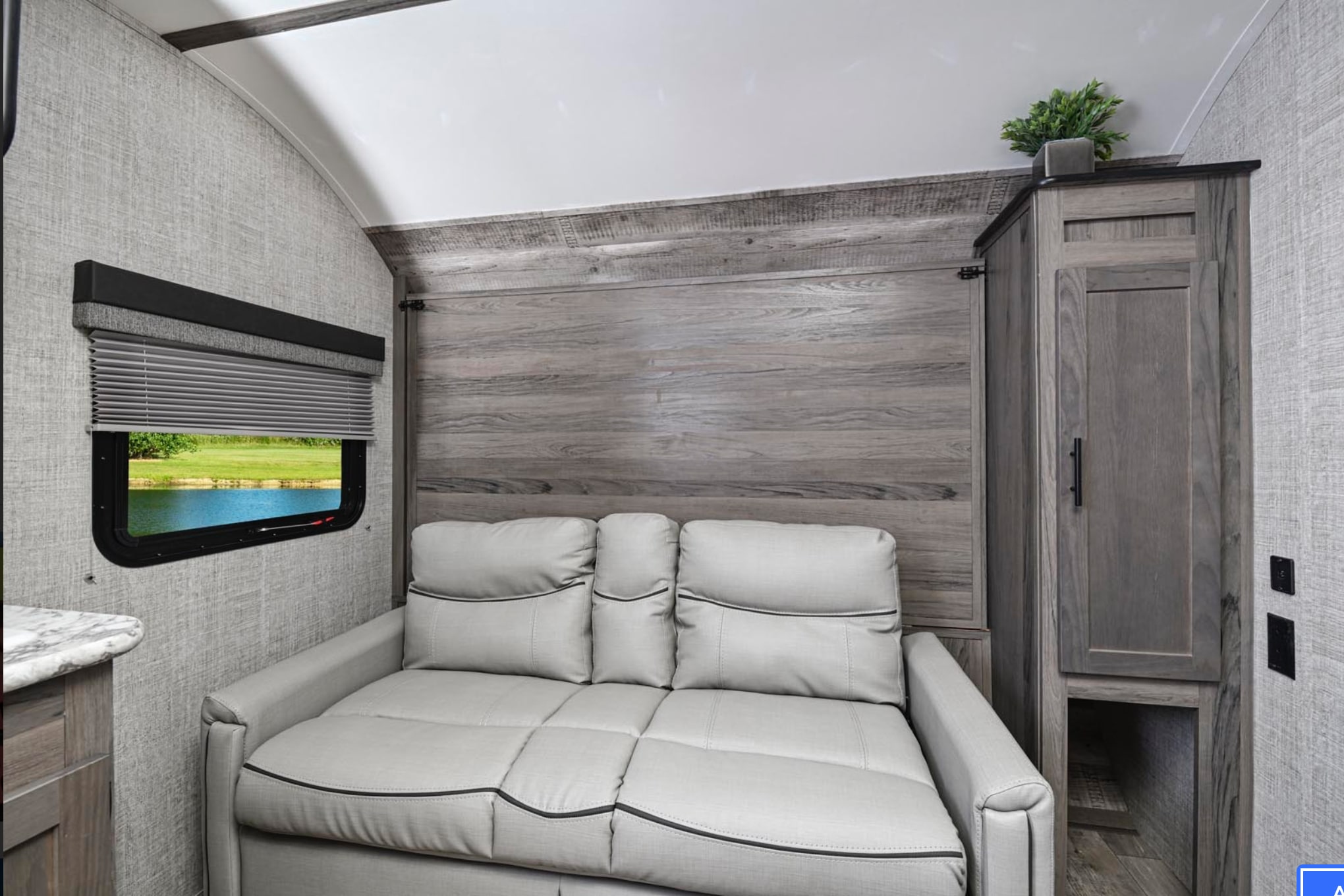 RV rental interior with a sleek gray convertible sofa, scenic window, and built-in storage maximizing comfort.. Gulf Stream Trailmaster Super Lite 2022