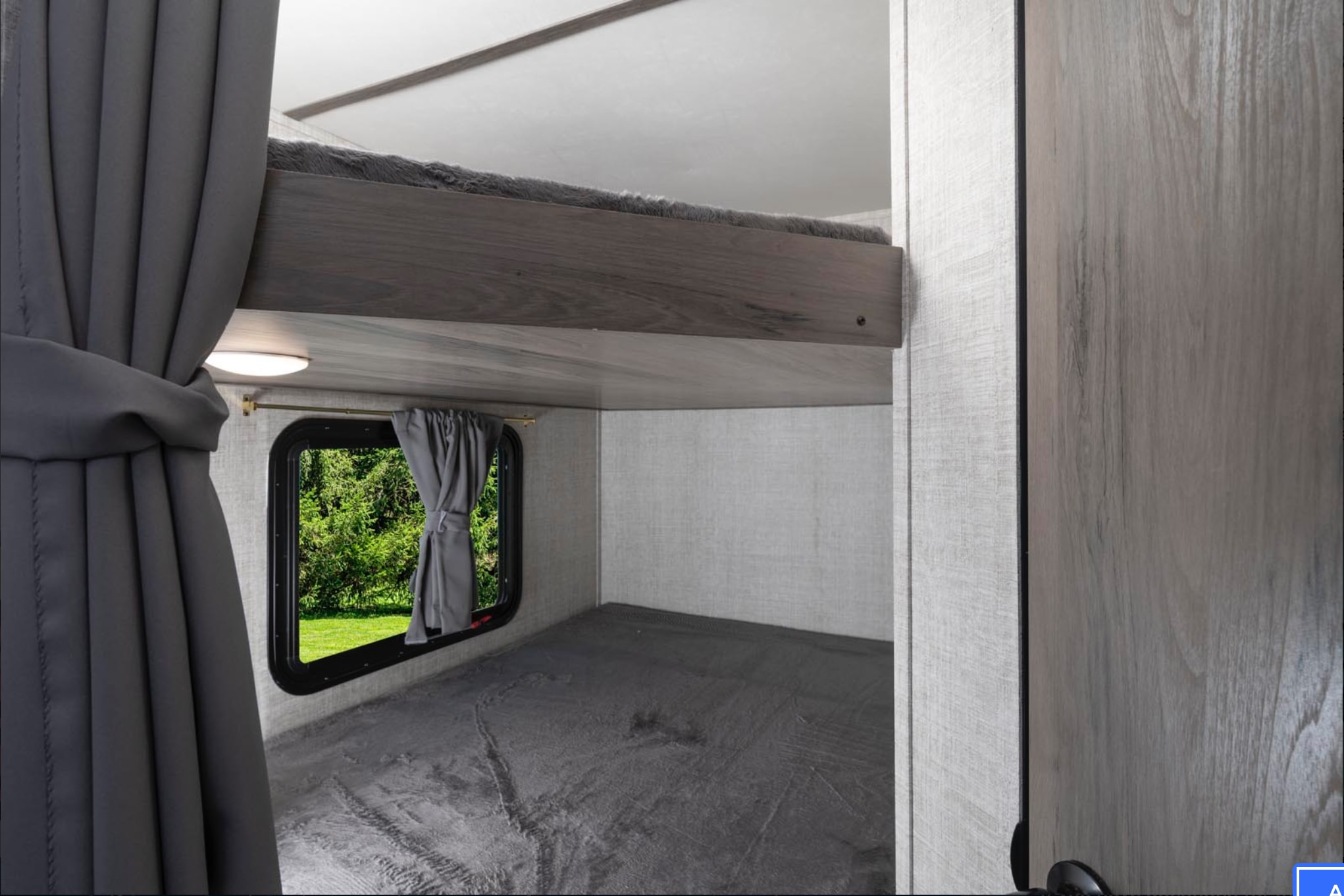 Inside an RV rental: upper and lower bunk beds with a window view of lush greenery. Ideal for families and group travel.. Gulf Stream Trailmaster Super Lite 2022
