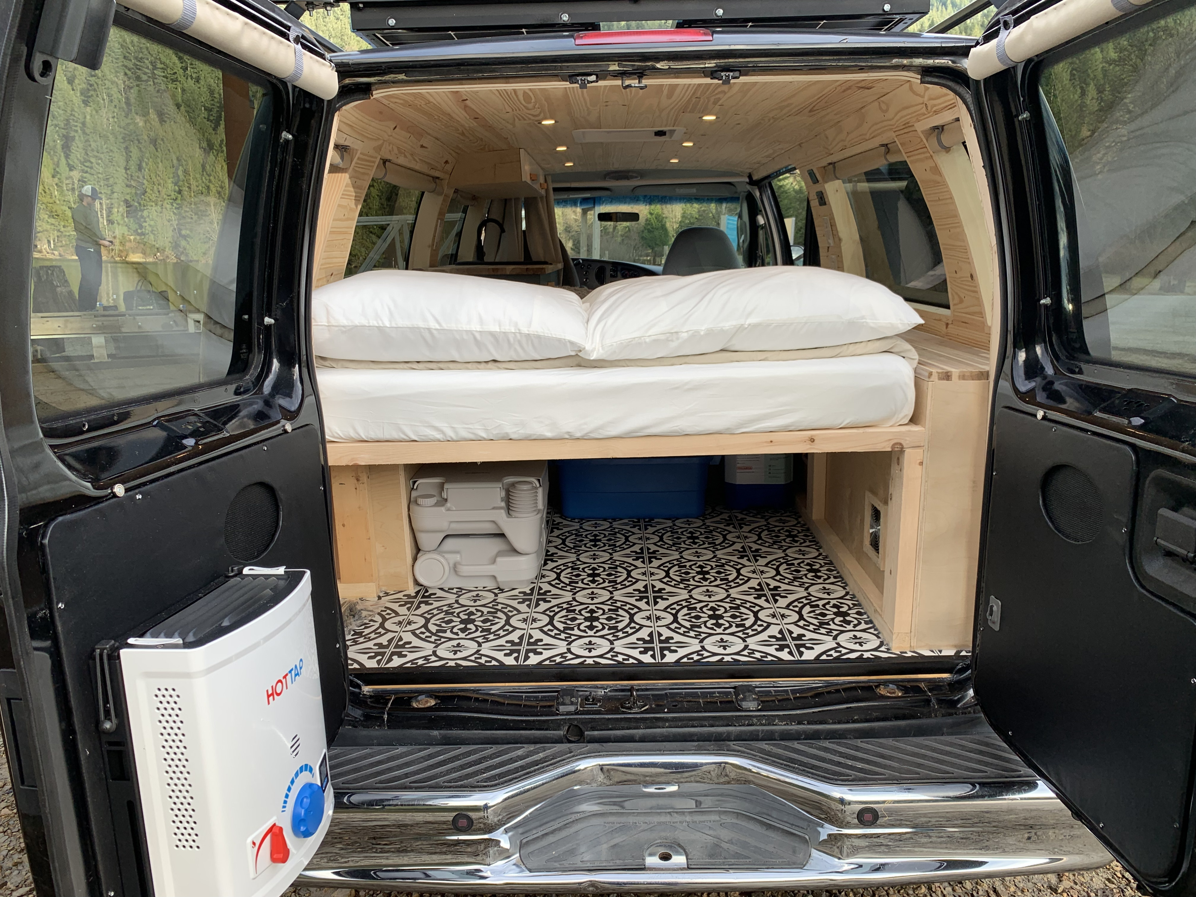 Inside a spacious, customized RV rental van with a bed, toilet, and water heater for comfortable travels & outdoor adventures.. Ford E350 Box Van 2007
