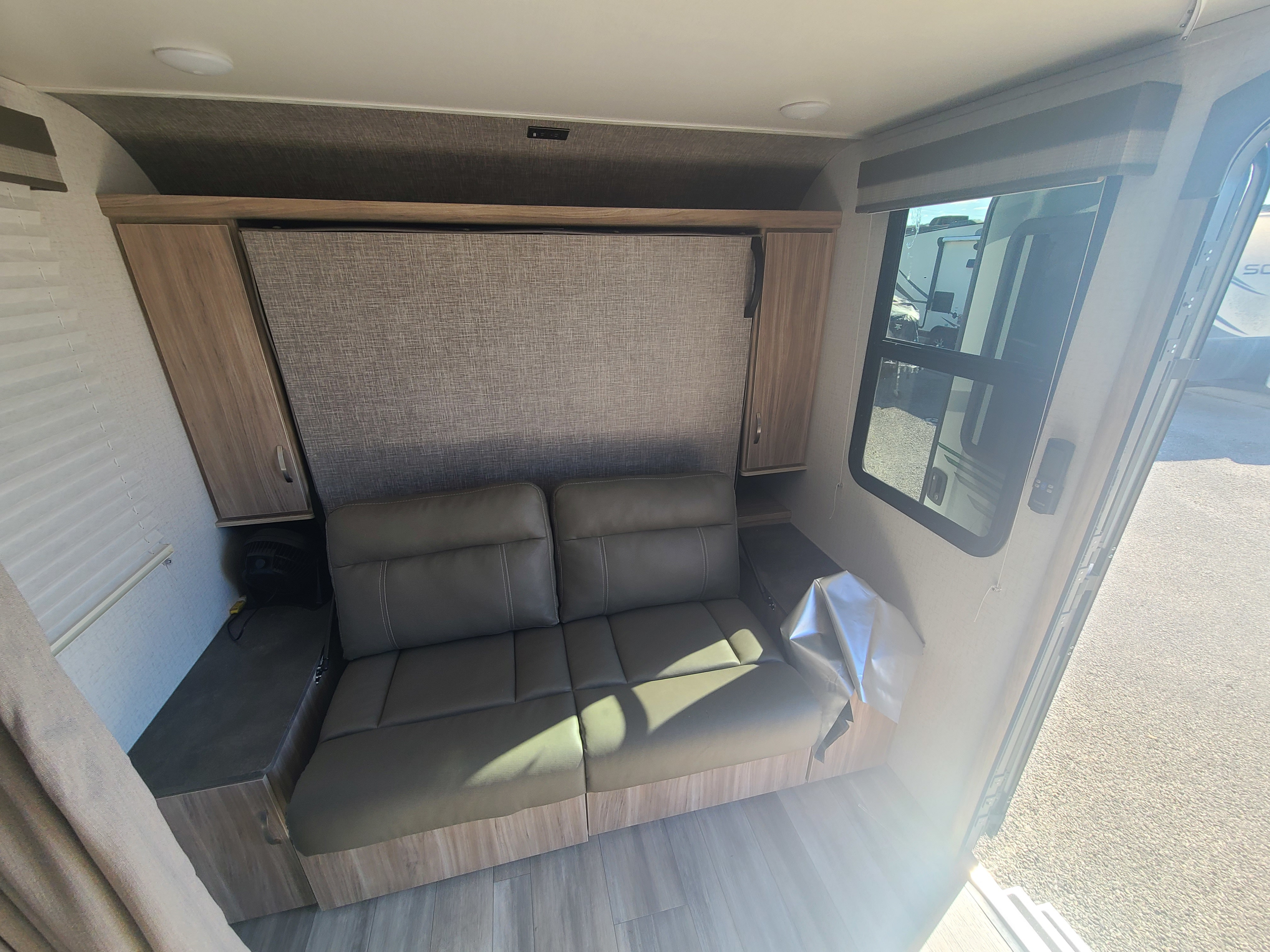 Spacious RV rental interior featuring a versatile sofa-bed, wood cabinetry, and bright window for a comfortable adventure.. Winnebago Micro Minnie FLX 2022