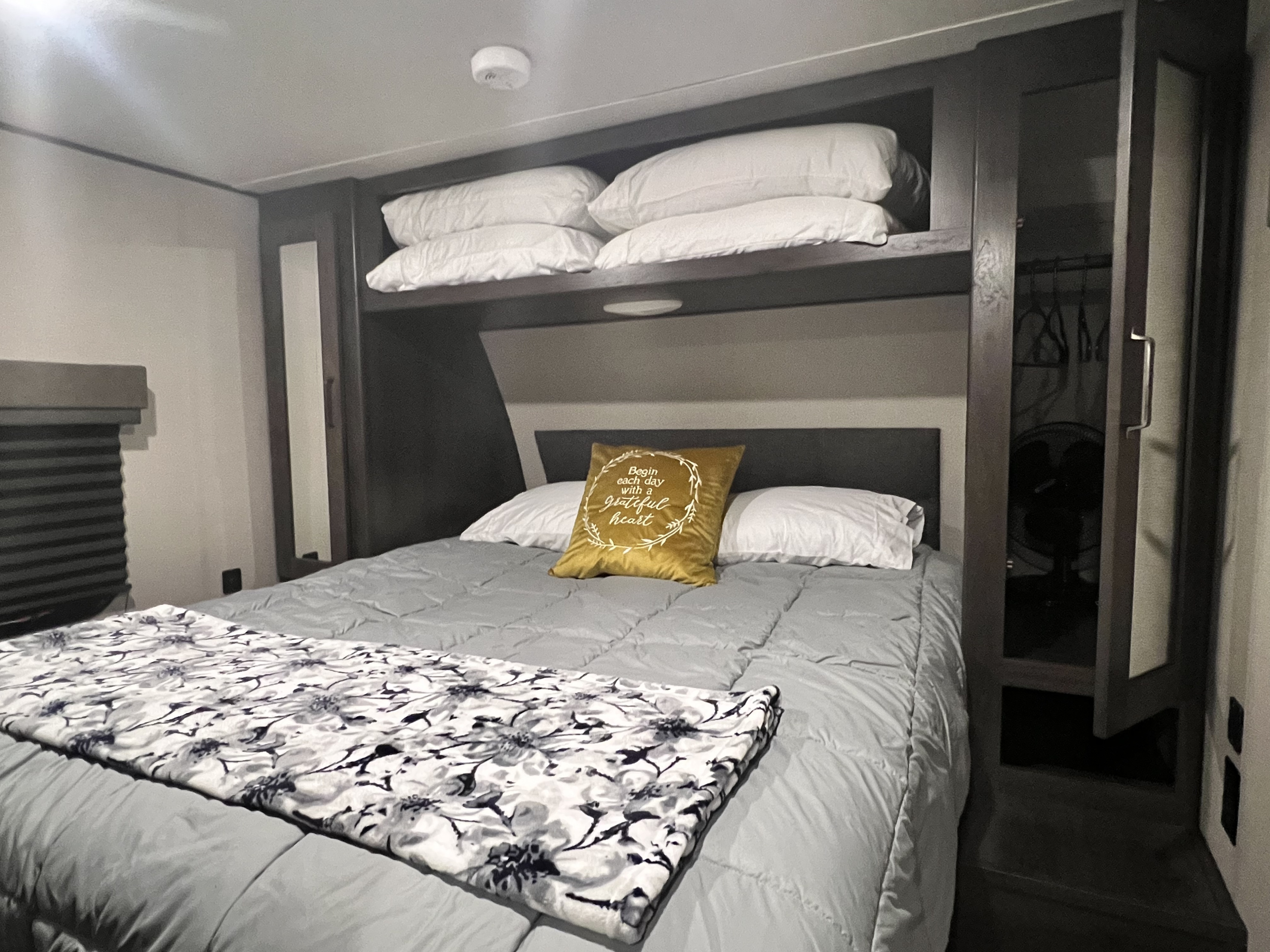 Cozy RV rental bedroom with a comfortable bed, decorative pillow, overhead storage, and a closet. Ideal for your travels.. Grand Design Transcend Xplor 2022