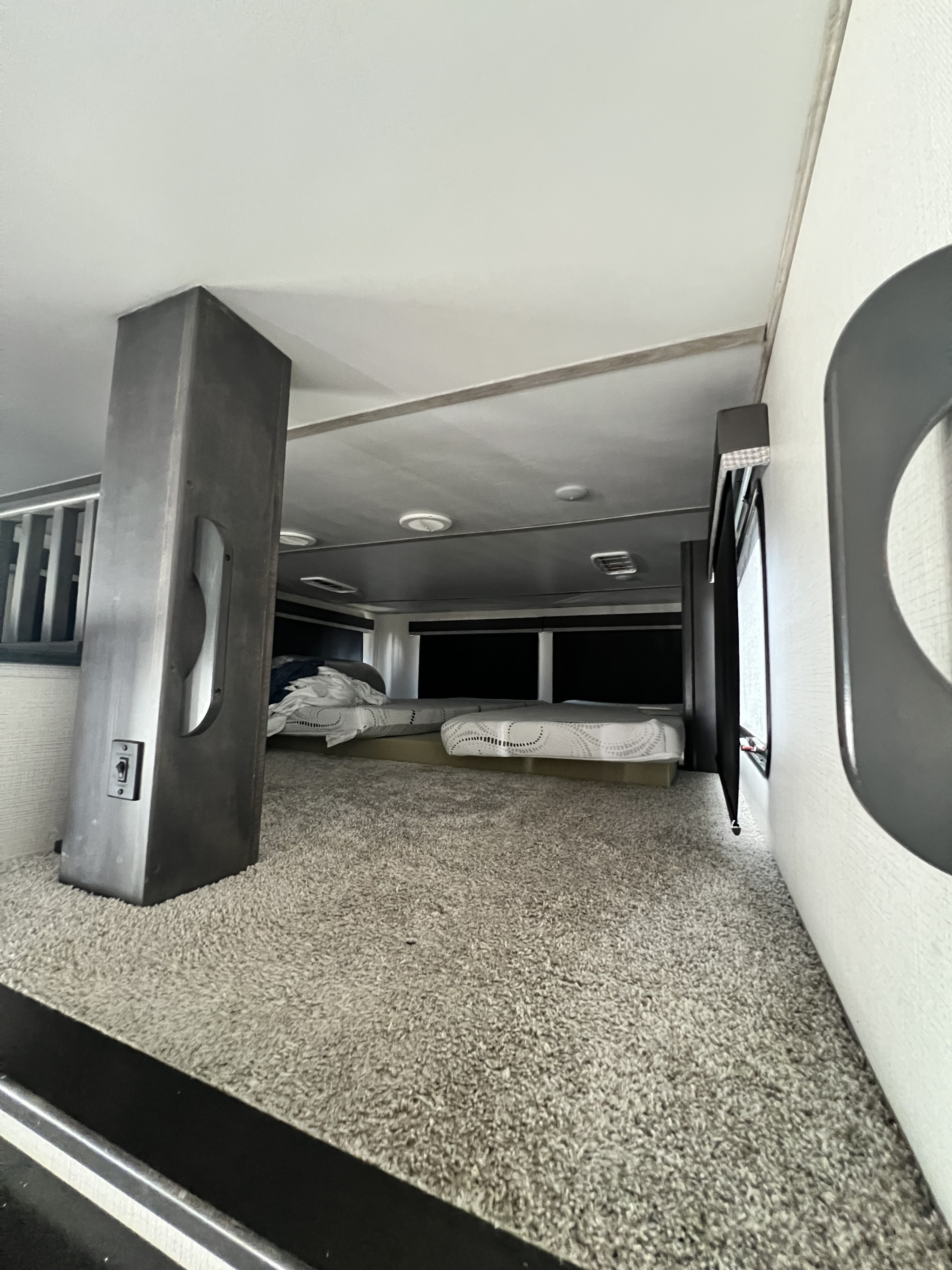 RV rental's carpeted loft bedroom: two mattresses with dark blinds in back, large support column on left.. Keystone Avalanche 2022