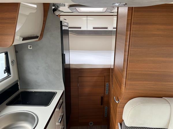 Cozy RV rental interior featuring a compact kitchen with sink/stove and a comfortable bedroom area.. Elnagh BARON 531 2023