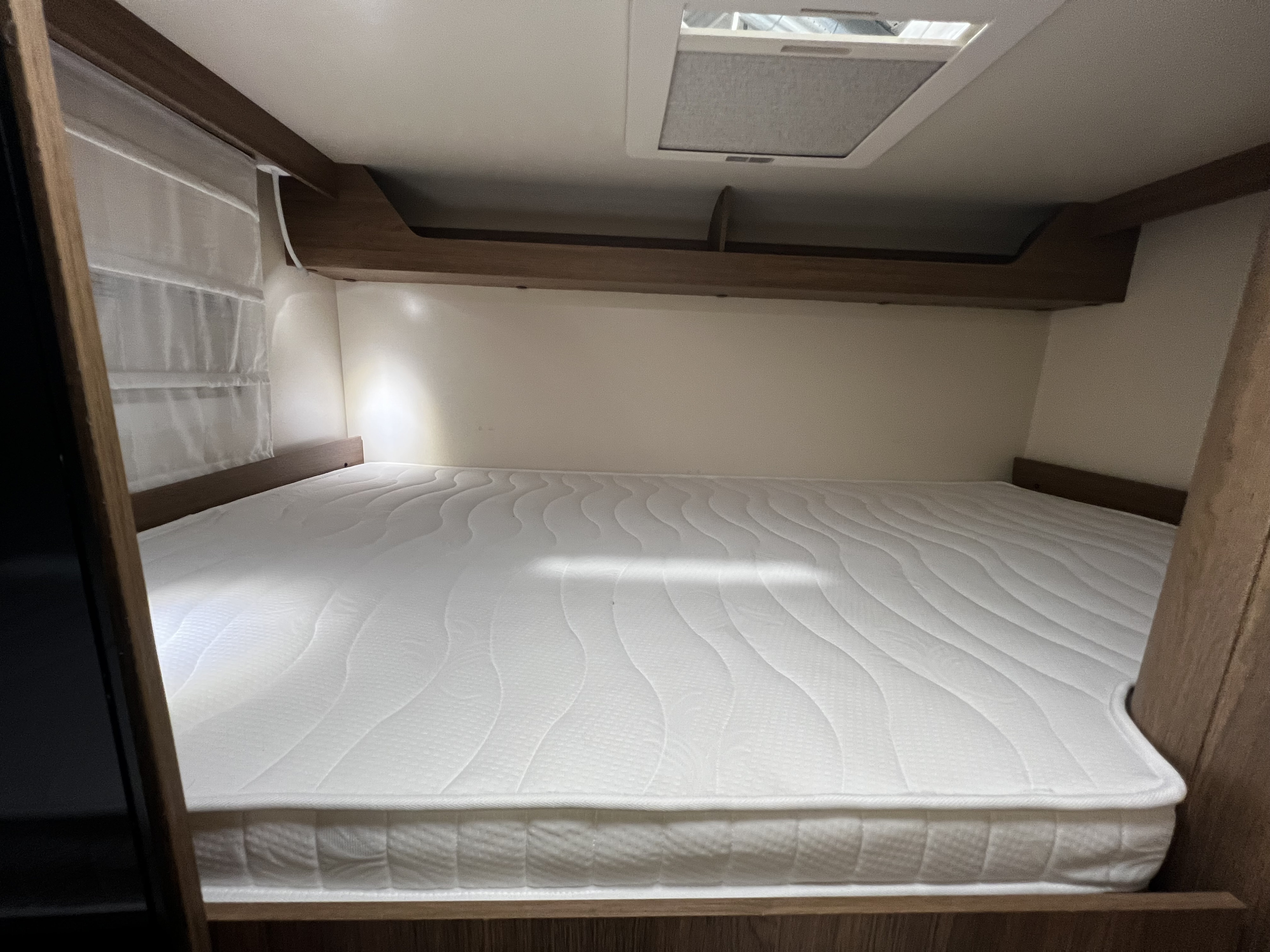 Cozy RV rental sleeping area with clean white mattress & skylight for comfortable travel.. Elnagh Baron 20 2023