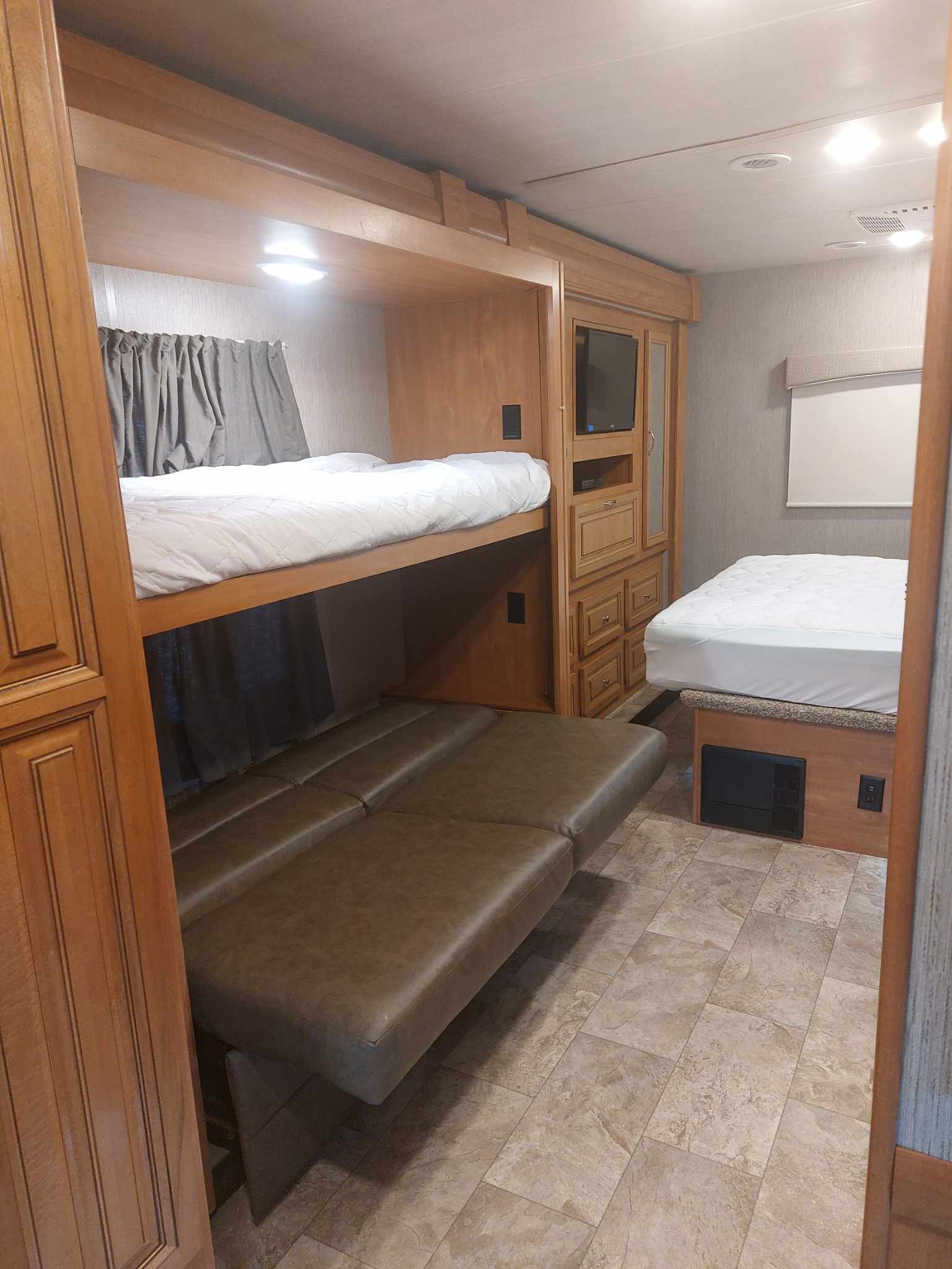 RV rental interior: bunk beds, convertible sofa, and a main bed, offering compact and comfortable sleeping arrangements.. Nexus RV Wraith 2021