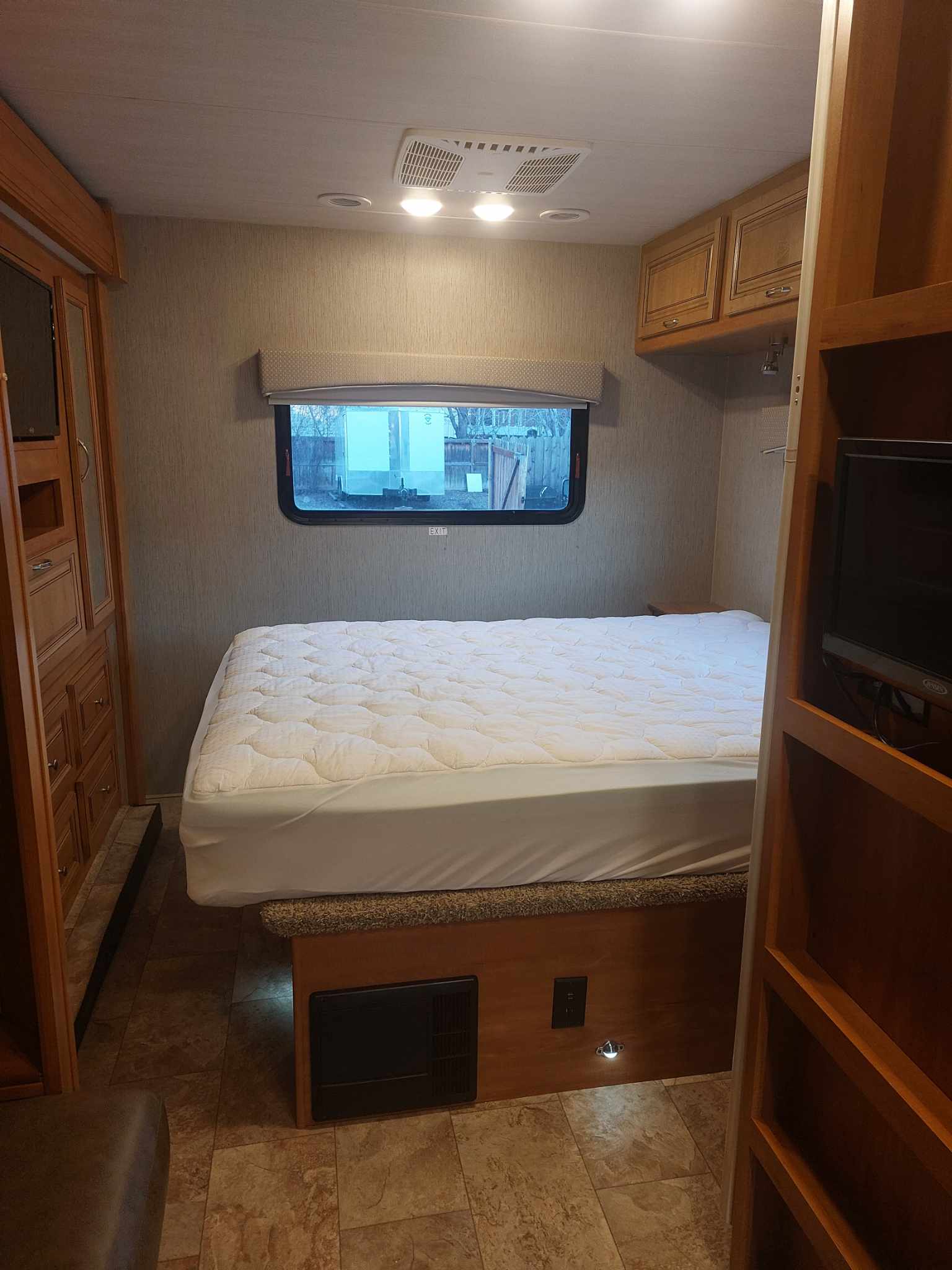 RV rental bedroom: a cozy space with a bed, white quilted topper, wood cabinets, and functional lighting.. Nexus RV Wraith 2021
