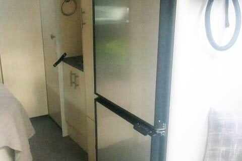 RV rental interior: light-toned cabinetry, frosted glass door, and a bed in a compact, functional space.. Airstream Flying Cloud 2022