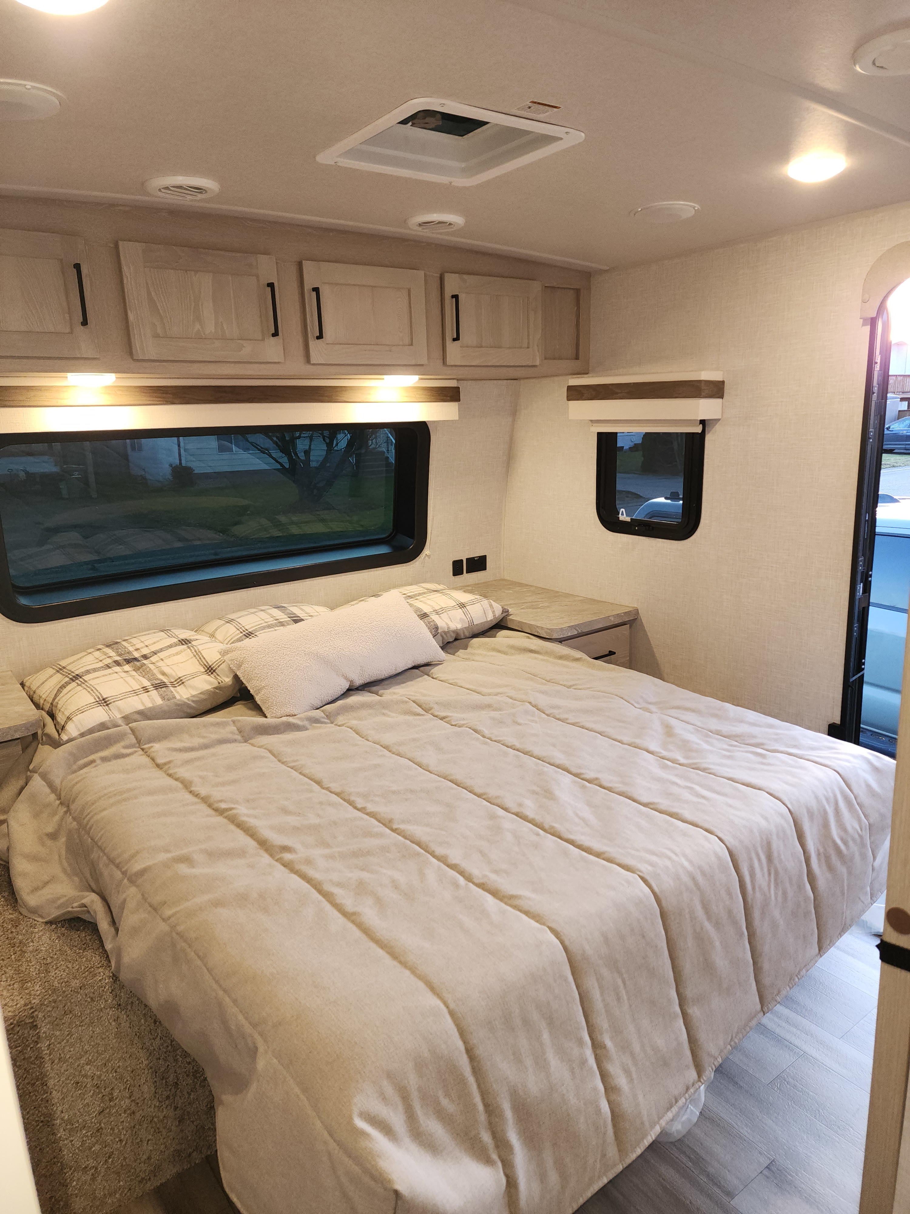 Comfortable RV rental bedroom with a large bed, overhead storage, side tables, and bright windows for a cozy retreat.. Forest River Rockwood Ultra Lite 2022