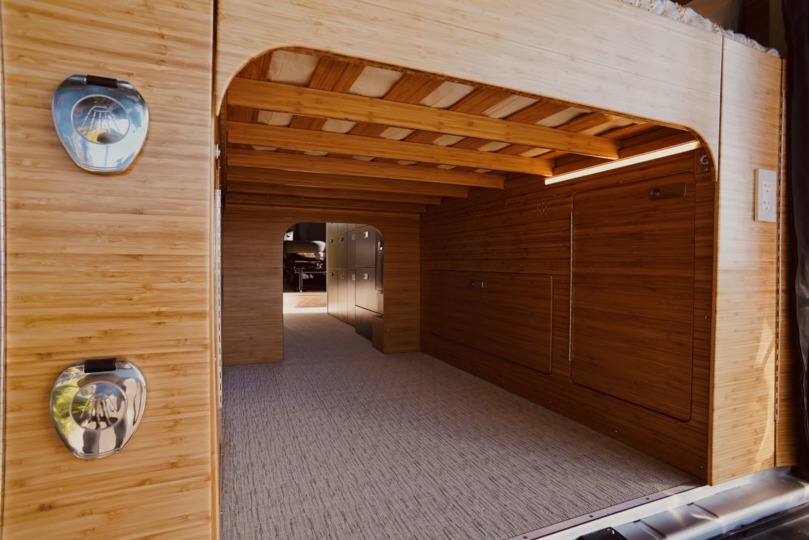 Step inside this custom rv rental: a warm, organized bamboo wood interior with a bunk bed, carpeted floor, and ample storage.. Noovo Lite 2023