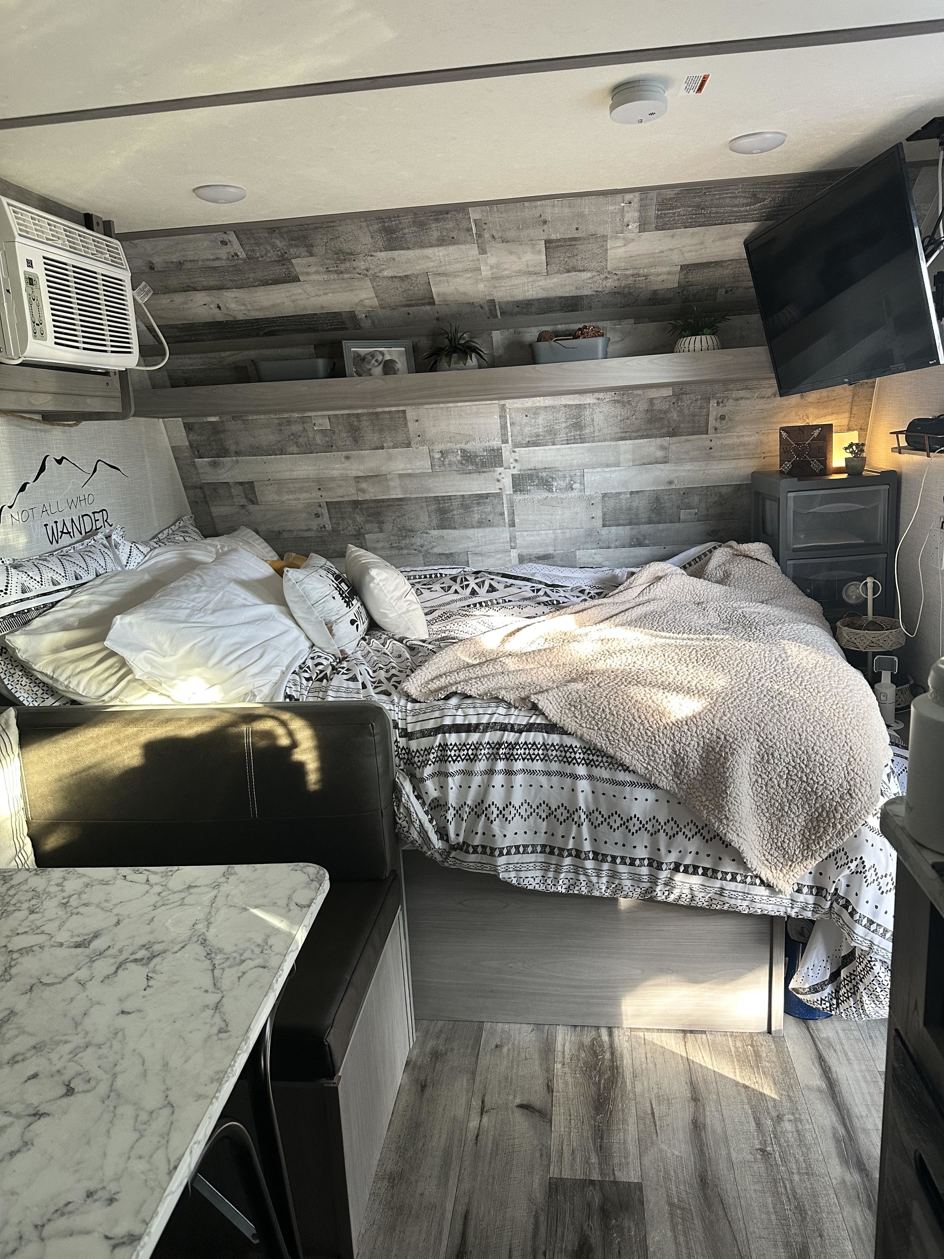 Cozy rv rental interior: patterned bed, AC, TV, and dinette. A comfortable, compact space for travel.. Coleman lantern 2024