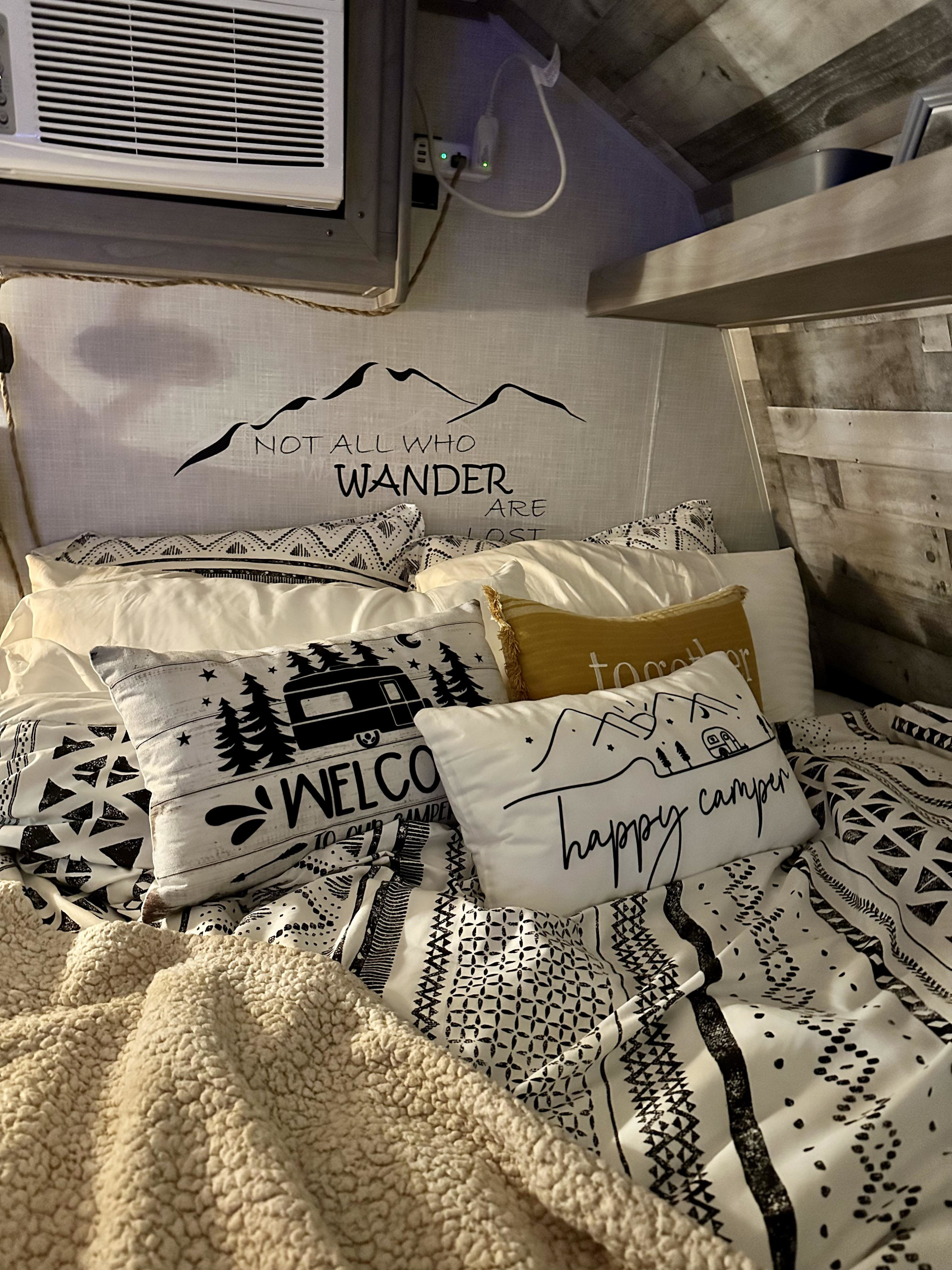 RV rental's cozy bed features "NOT ALL WHO WANDER ARE LOST" mountain wall decor & "happy camper" pillows.. Coleman lantern 2024