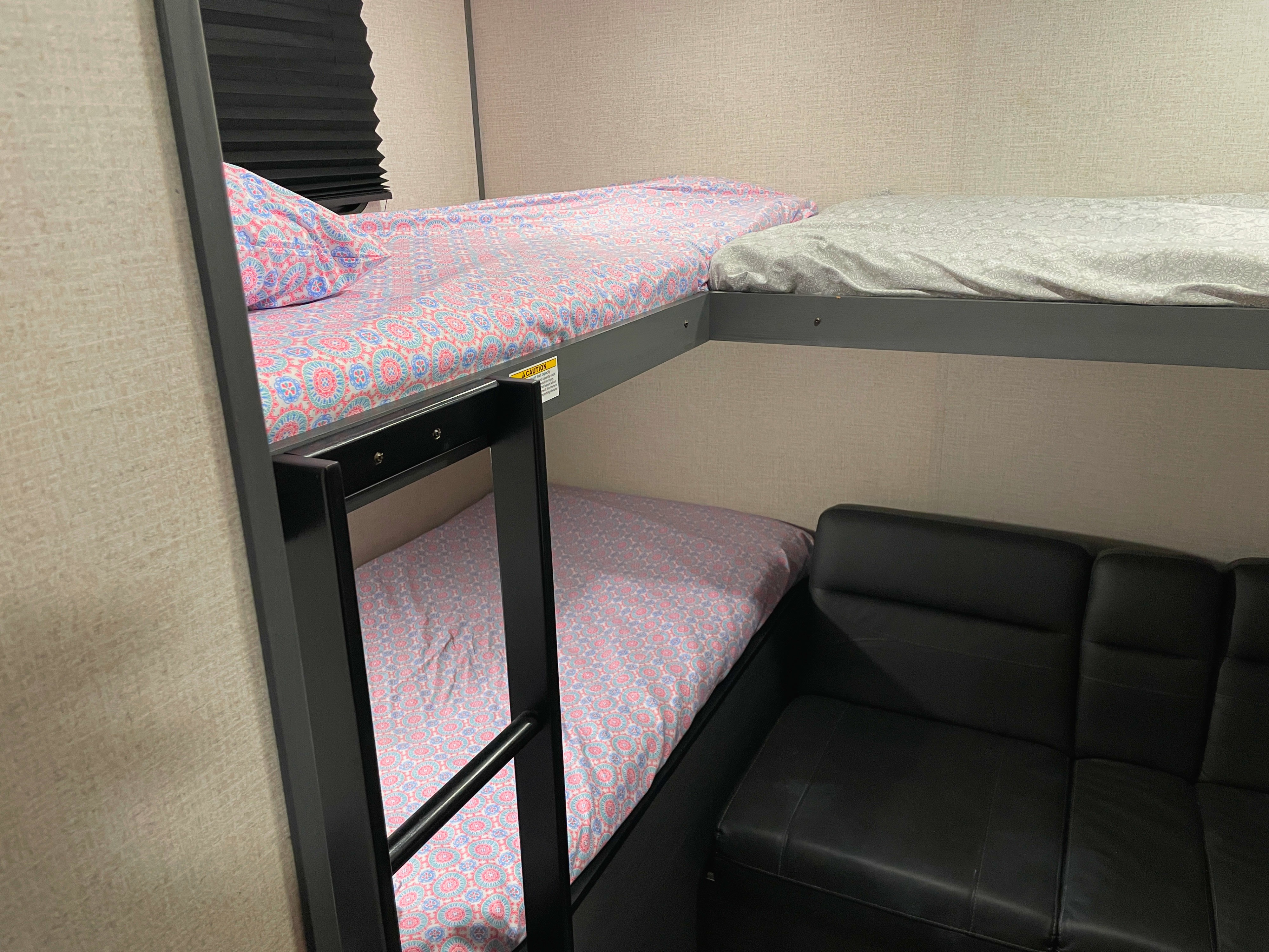 Enjoy an RV rental's clever use of space: stacked bunk beds with colorful sheets and a black seating area below.. Dutchmen Colorado 2023