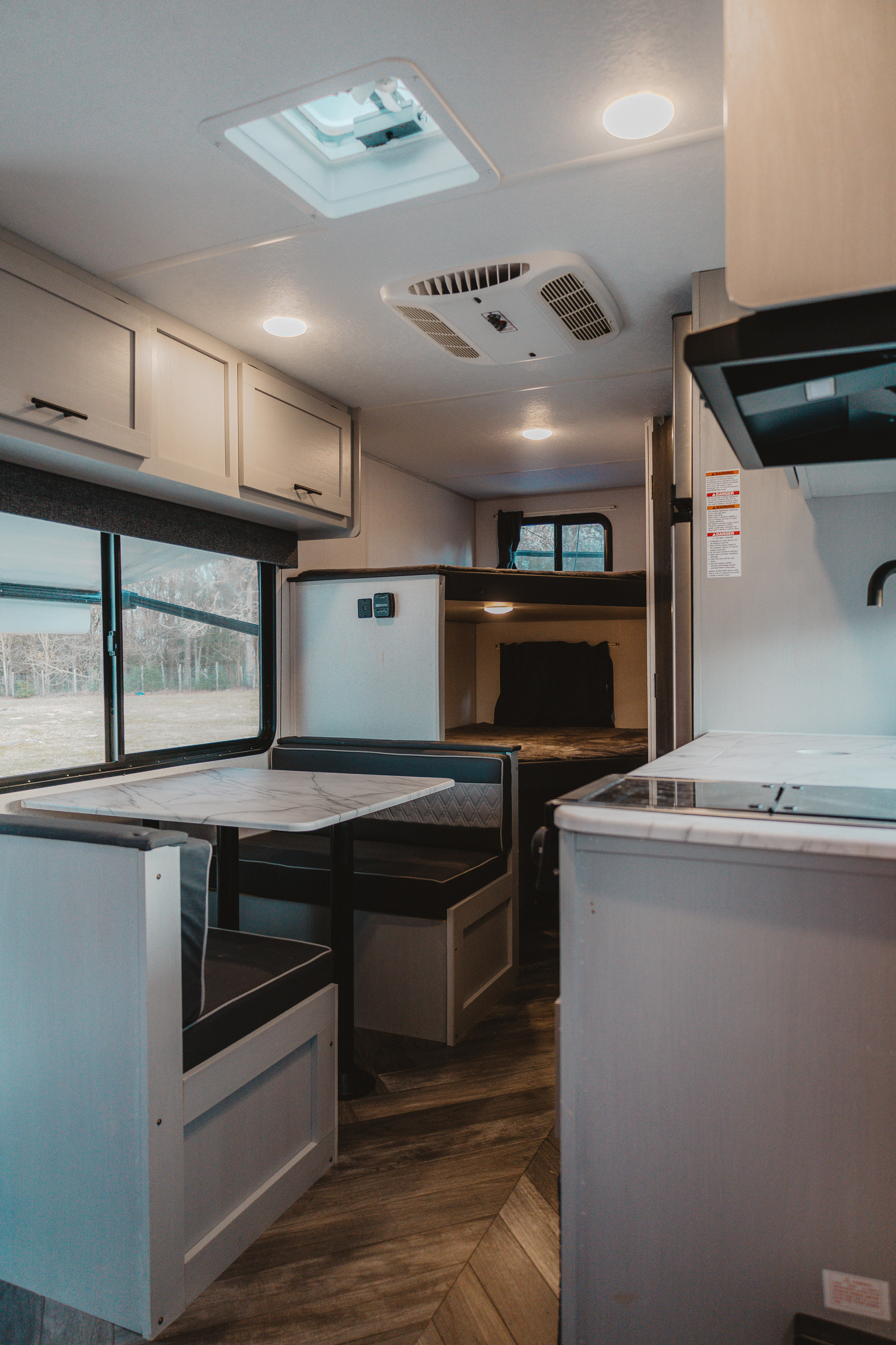 Spacious RV rental interior with a cozy dinette, overhead cabinets, roof vent, bunk beds, and a functional kitchen.. Forest River Wildwood FSX Plantium 2022