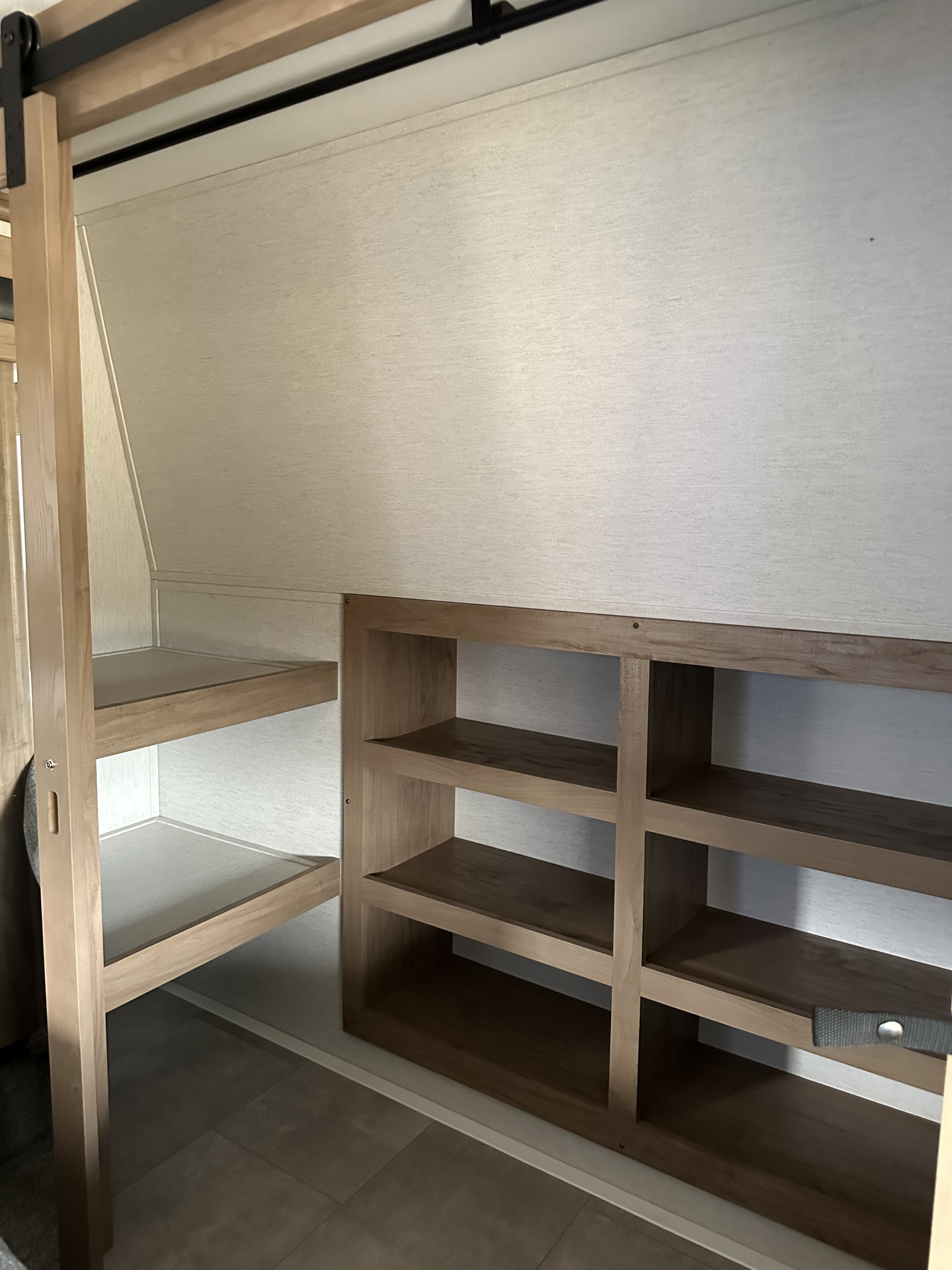 RV rental bedroom showcasing light wood bunk beds & ample built-in shelving for organized storage, ideal for family travel.. Forest River Vengeance Rogue Amored Toy Hauler 2023