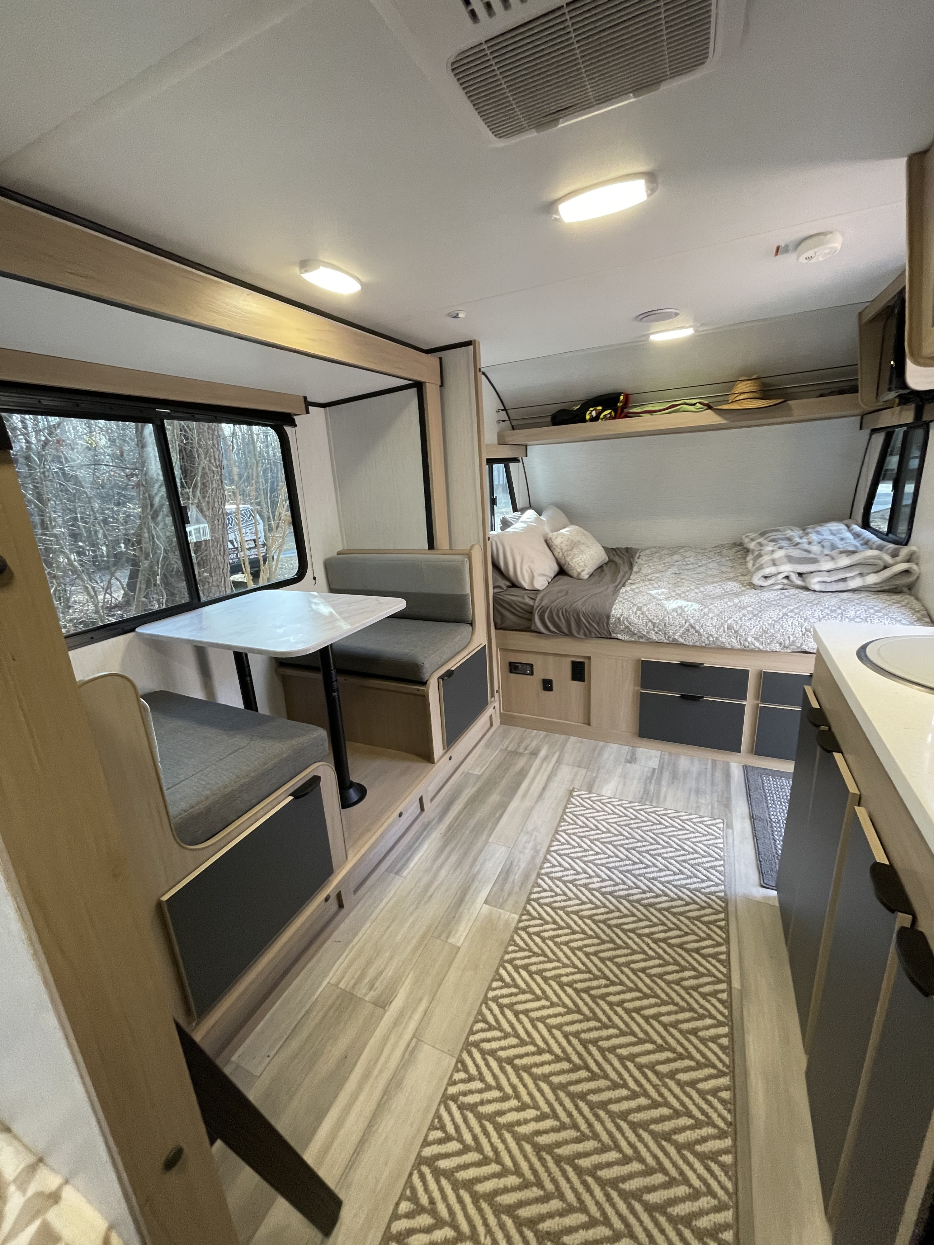 This rv rental interior features a dinette, sleeping area with bed, overhead bunk storage, and a kitchen counter. Bright and functional.. Cruiser RV Hitch 2022