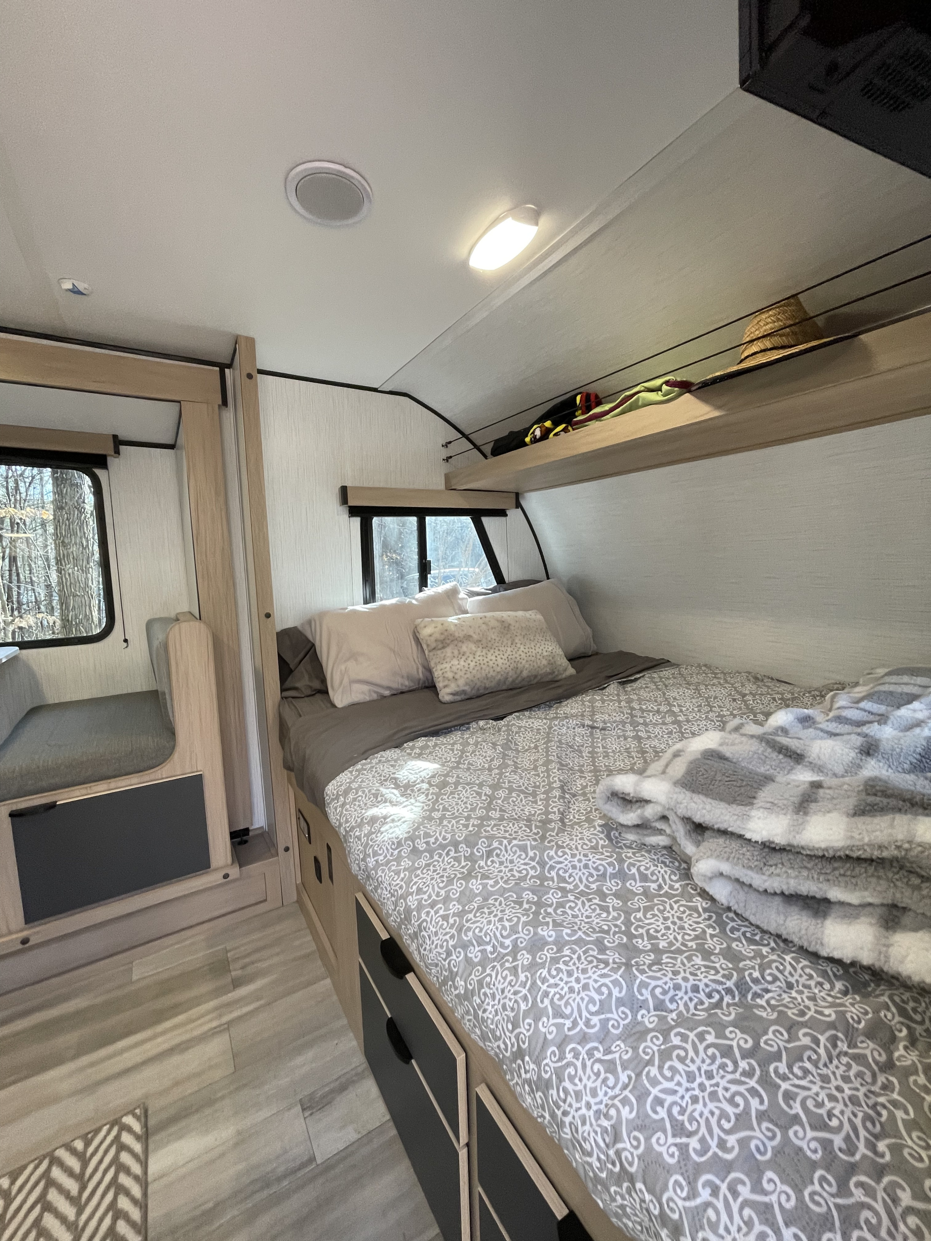 Inside a comfortable RV rental: bed with storage, compact dinette, and overhead shelf. Ideal for road trips.. Cruiser RV Hitch 2022