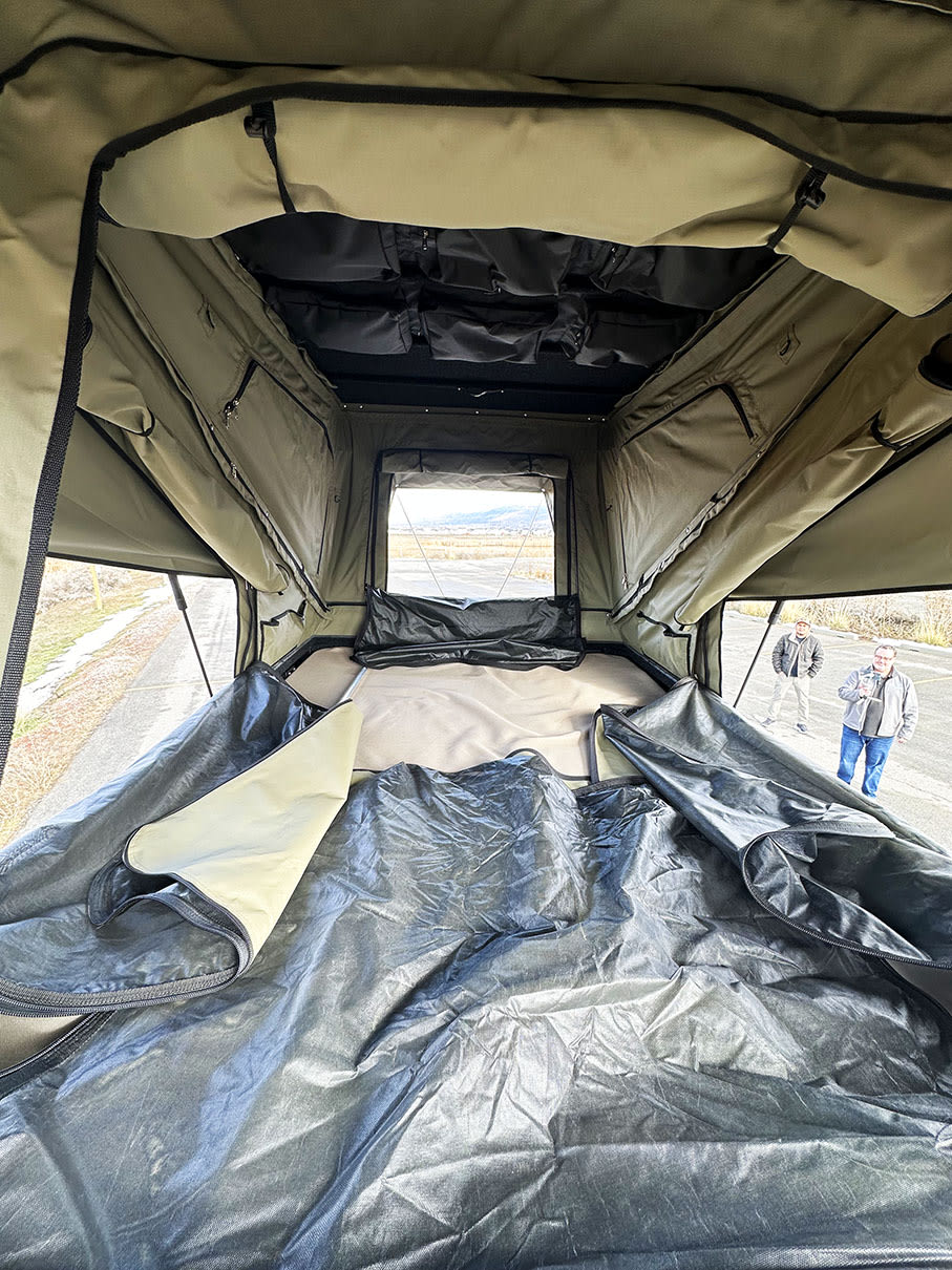 Inside a large rooftop tent, highlighting its mattress, storage, and scenic outdoor view. Ideal for RV rental road trips.. Other Other 2024